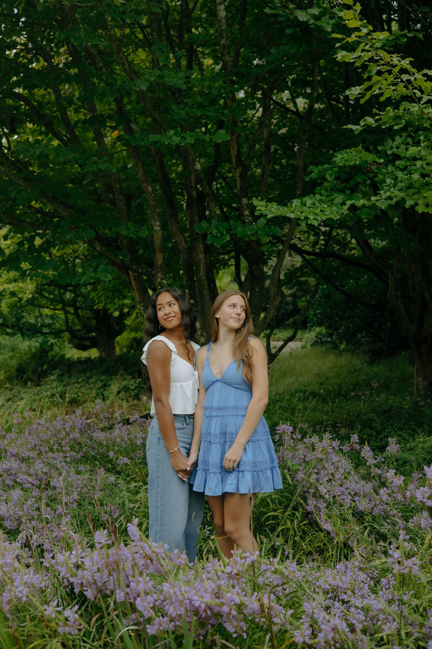 Friends posing together in a field of purple wildflowers surrounded by lush greenery.