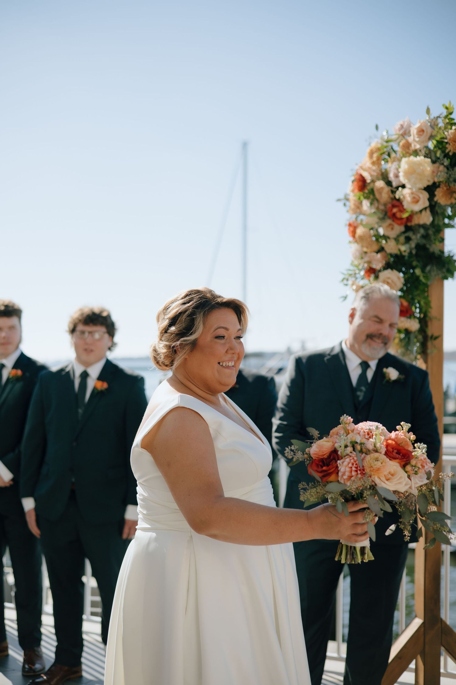 A joyful wedding ceremony taking place outdoors with floral arrangements and attendees in formal attire.