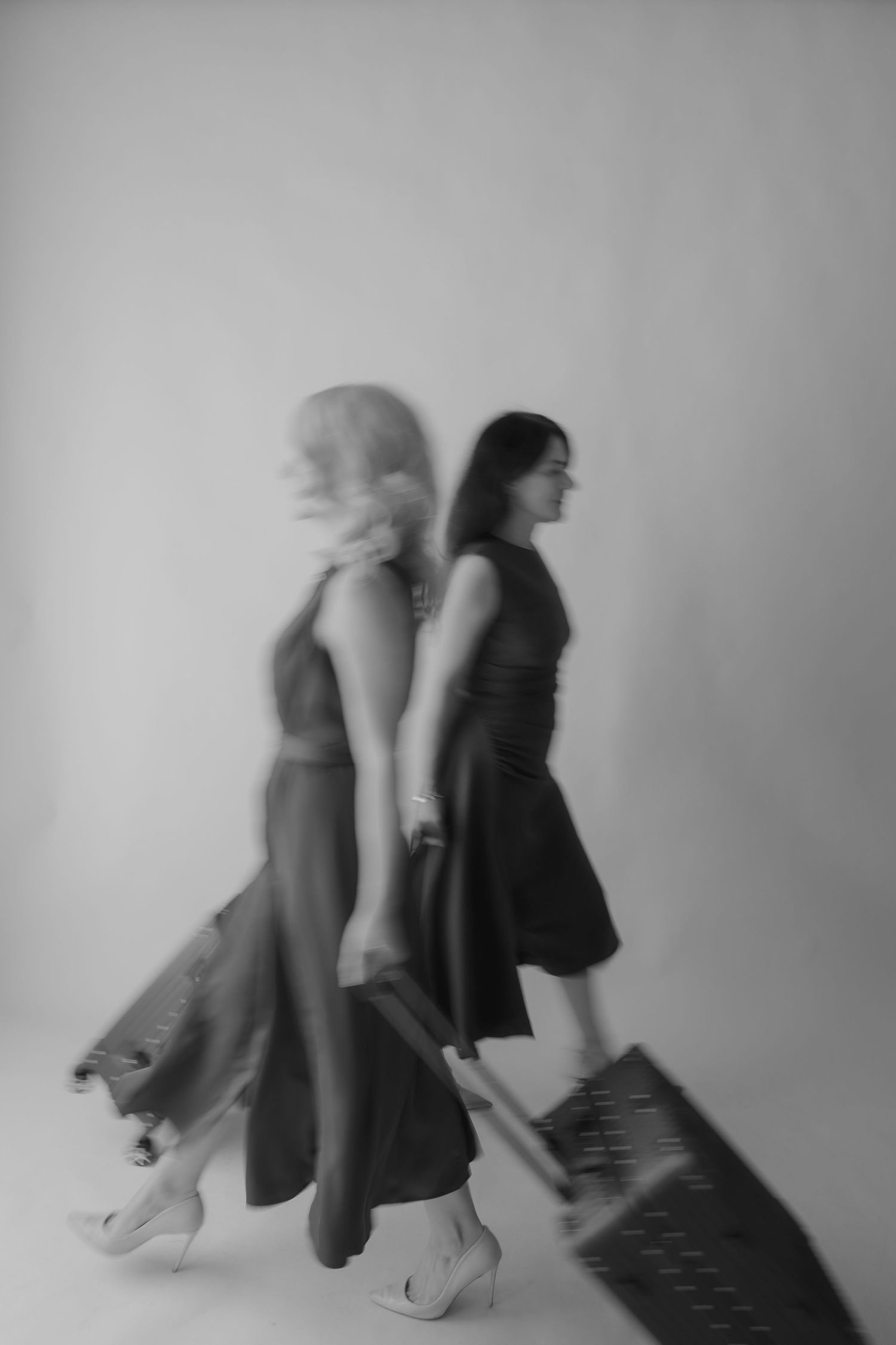 A sequence of black and white motion blur photos showing a person in a dress and heels moving against a wall.