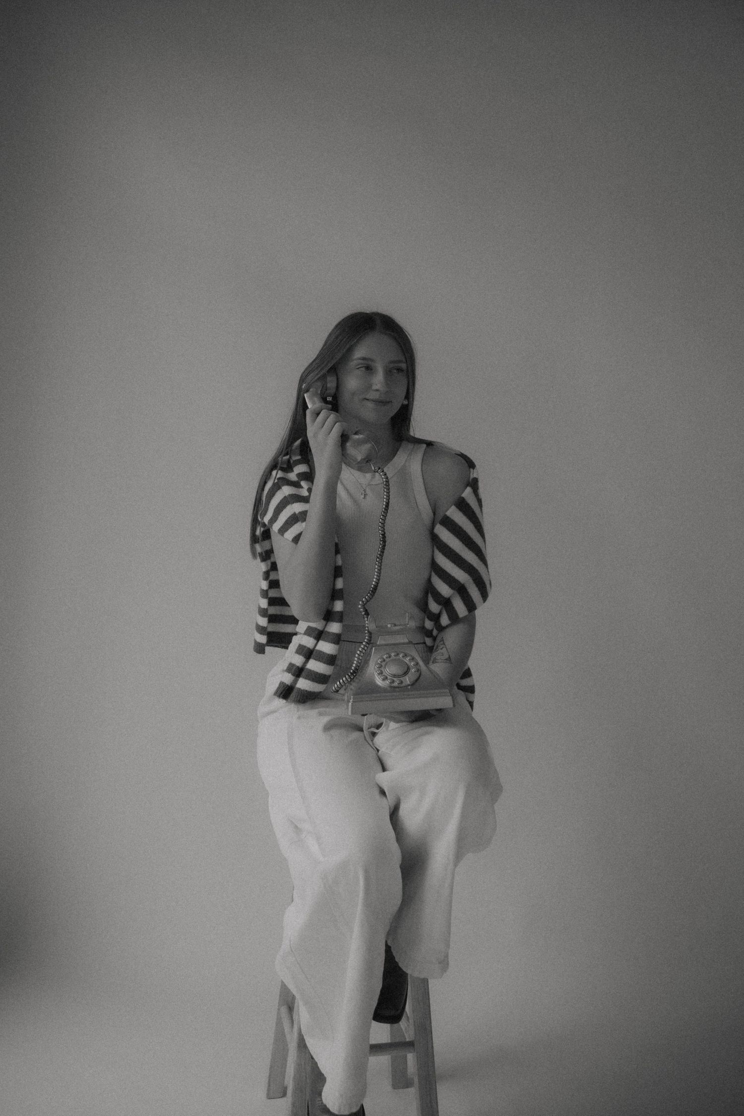 A series of black and white photos showing someone sitting on a stool in white clothing against a plain background.