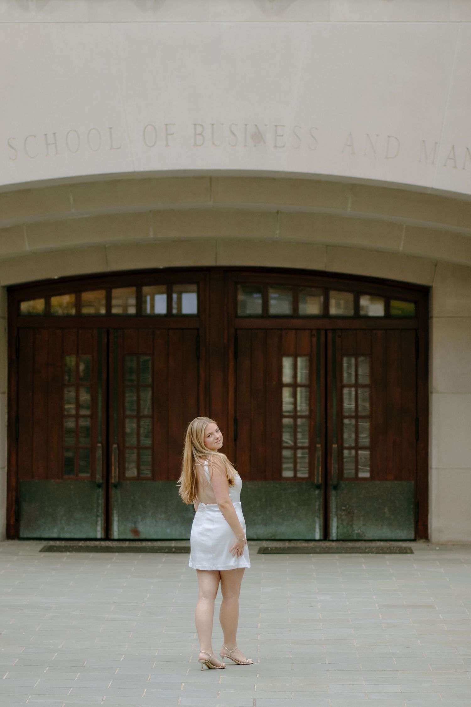 Wide shot of School of Business entrance with dark wooden doors and stone facade.