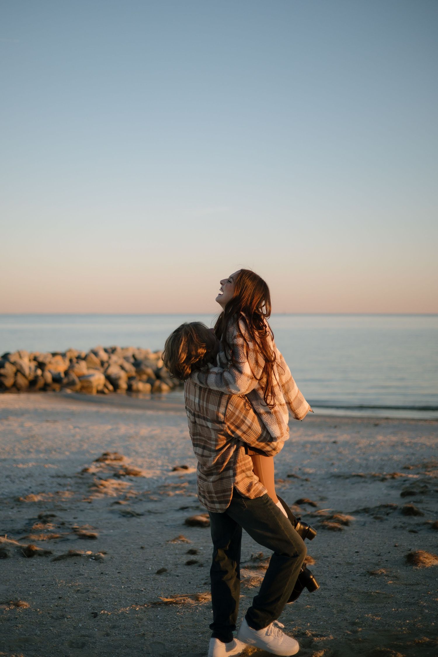 Silhouettes embrace and dance together on a sandy beach at dusk.