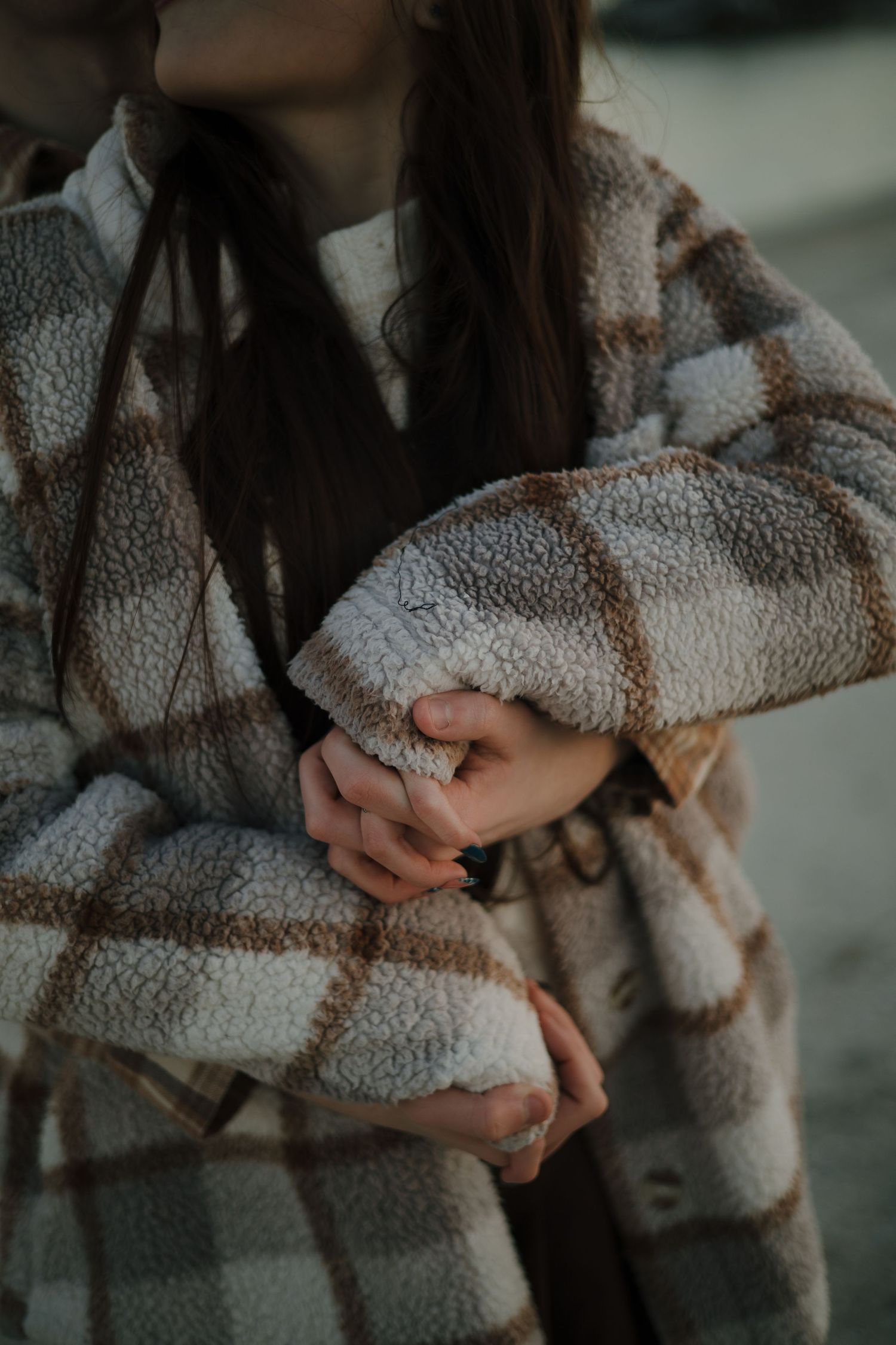 Close-up detail of a cozy plaid winter coat in muted tones.
