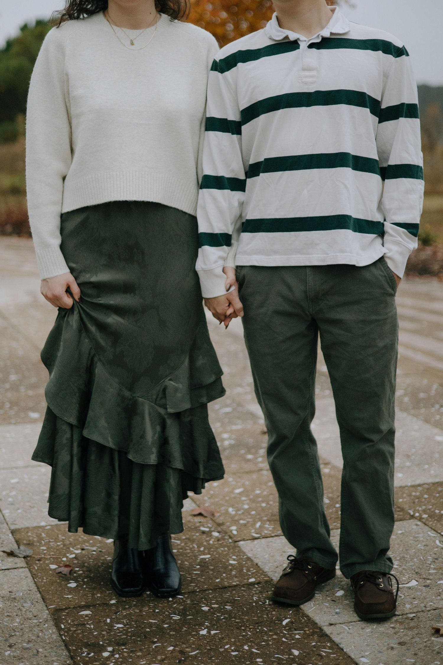 Two people in coordinating green and white outfits hold hands while standing together.