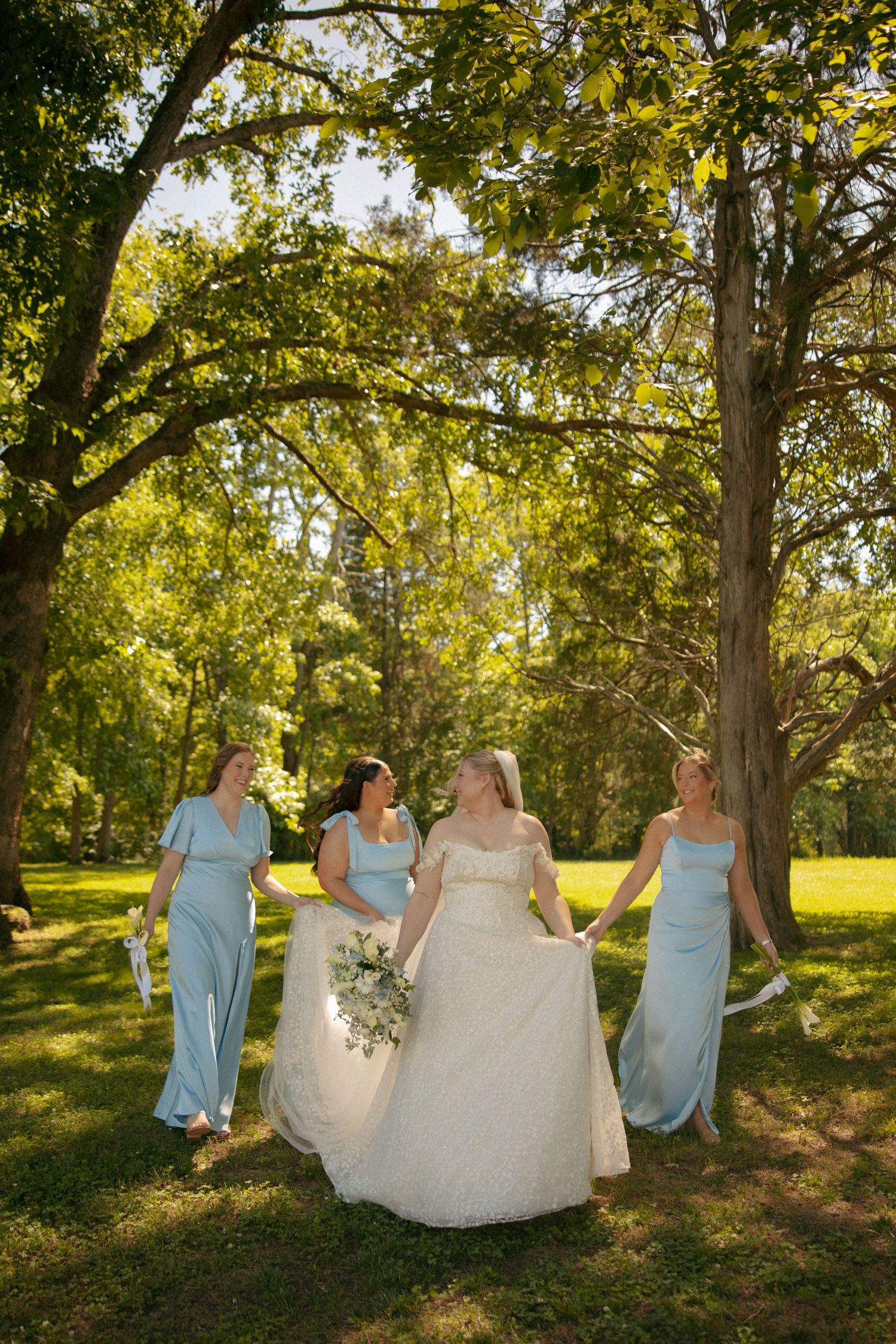 Bride in white gown walks with three bridesmaids in light blue dresses at Avonlea Farms in Mineral, VA.  Virginia Wedding Photographer