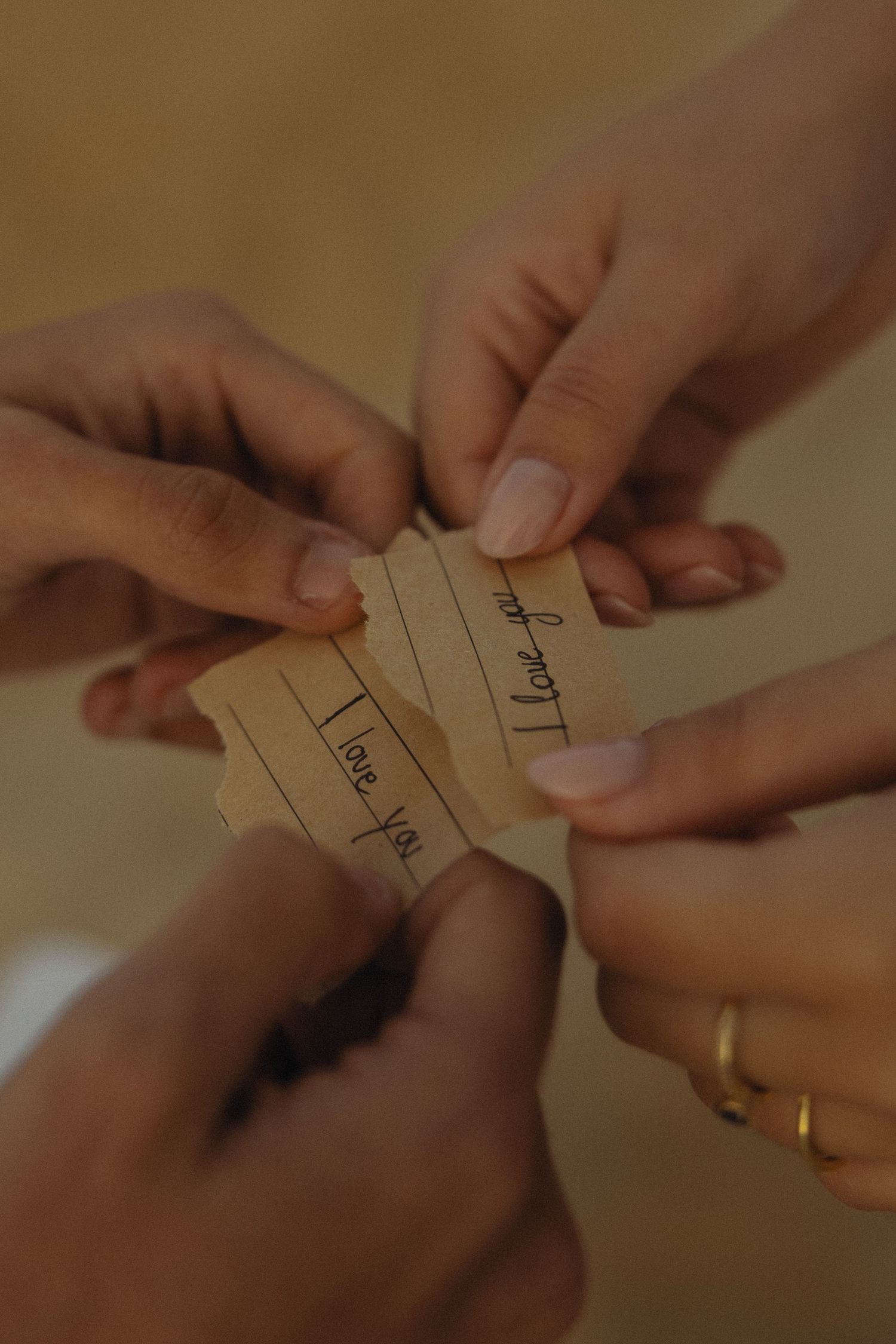 Multiple hands holding unfolded paper notes with 'I love you' written on them, sharing a heartfelt message together.