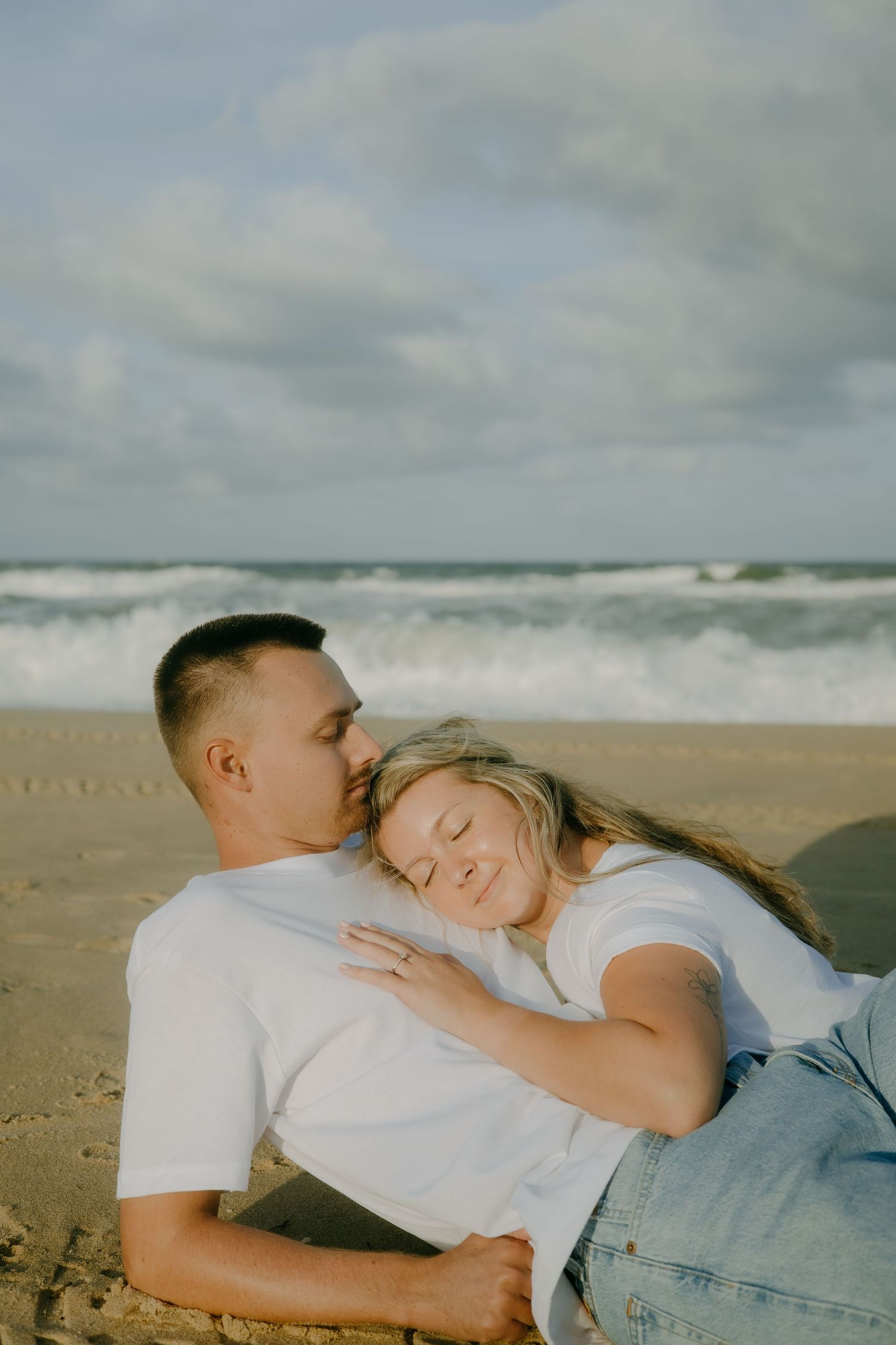 A couple sharing intimate moments while relaxing together on a sandy beach.