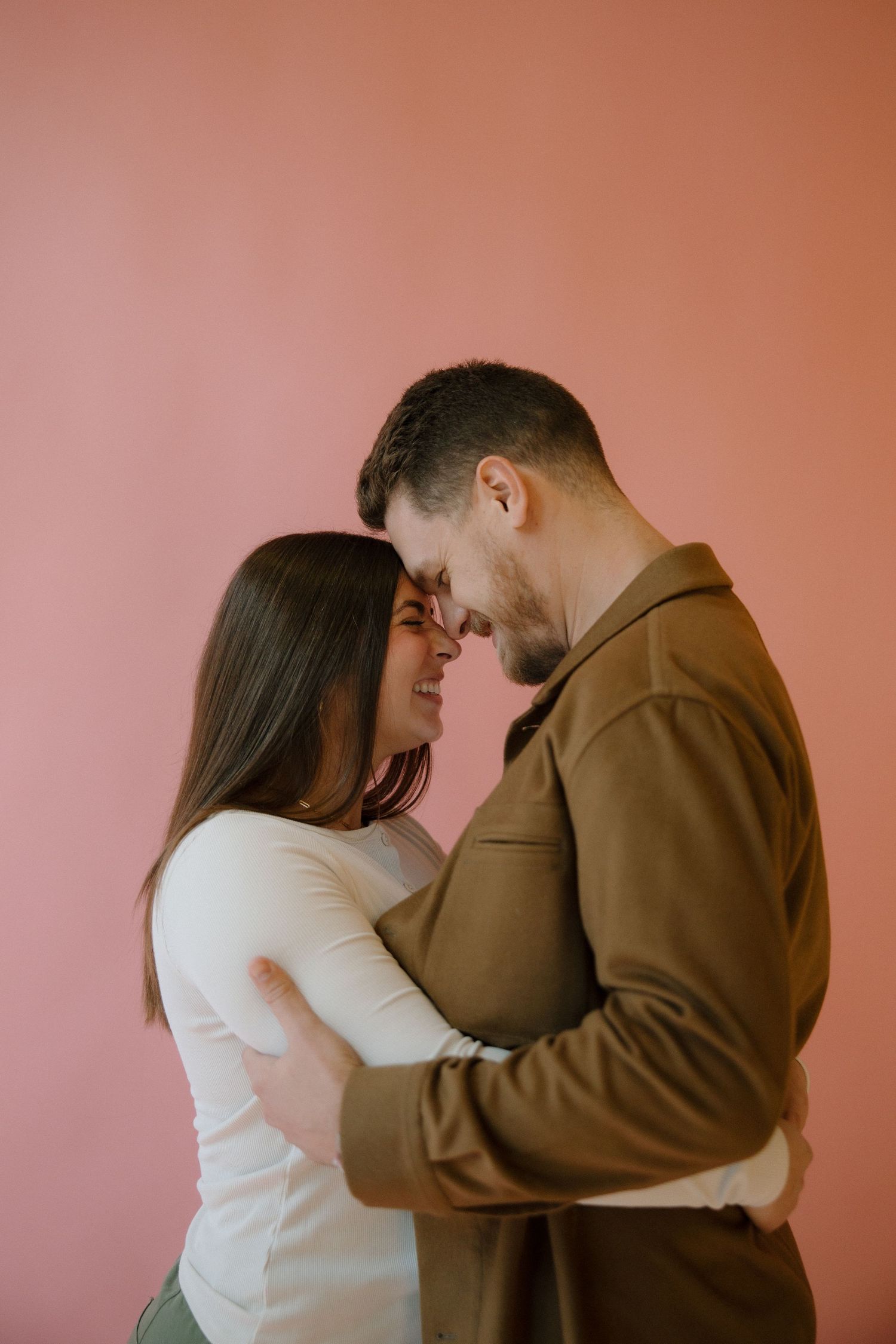Romantic couple against a pink background in a studio in richmond virginia captured by a virginia wedding and lifestyle photographer