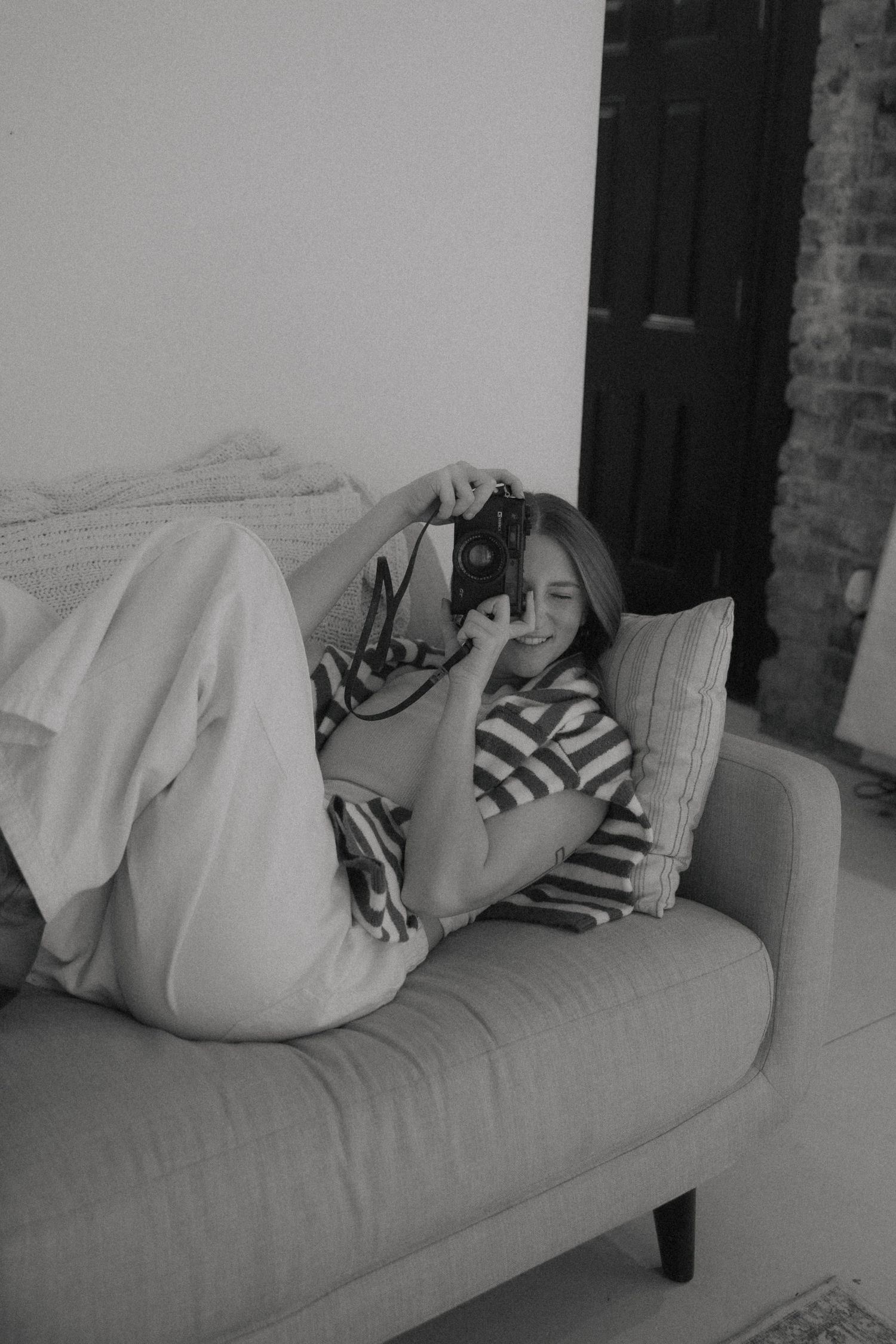 Black and white photo sequence of someone sleeping on a couch while gradually being covered by a white blanket.