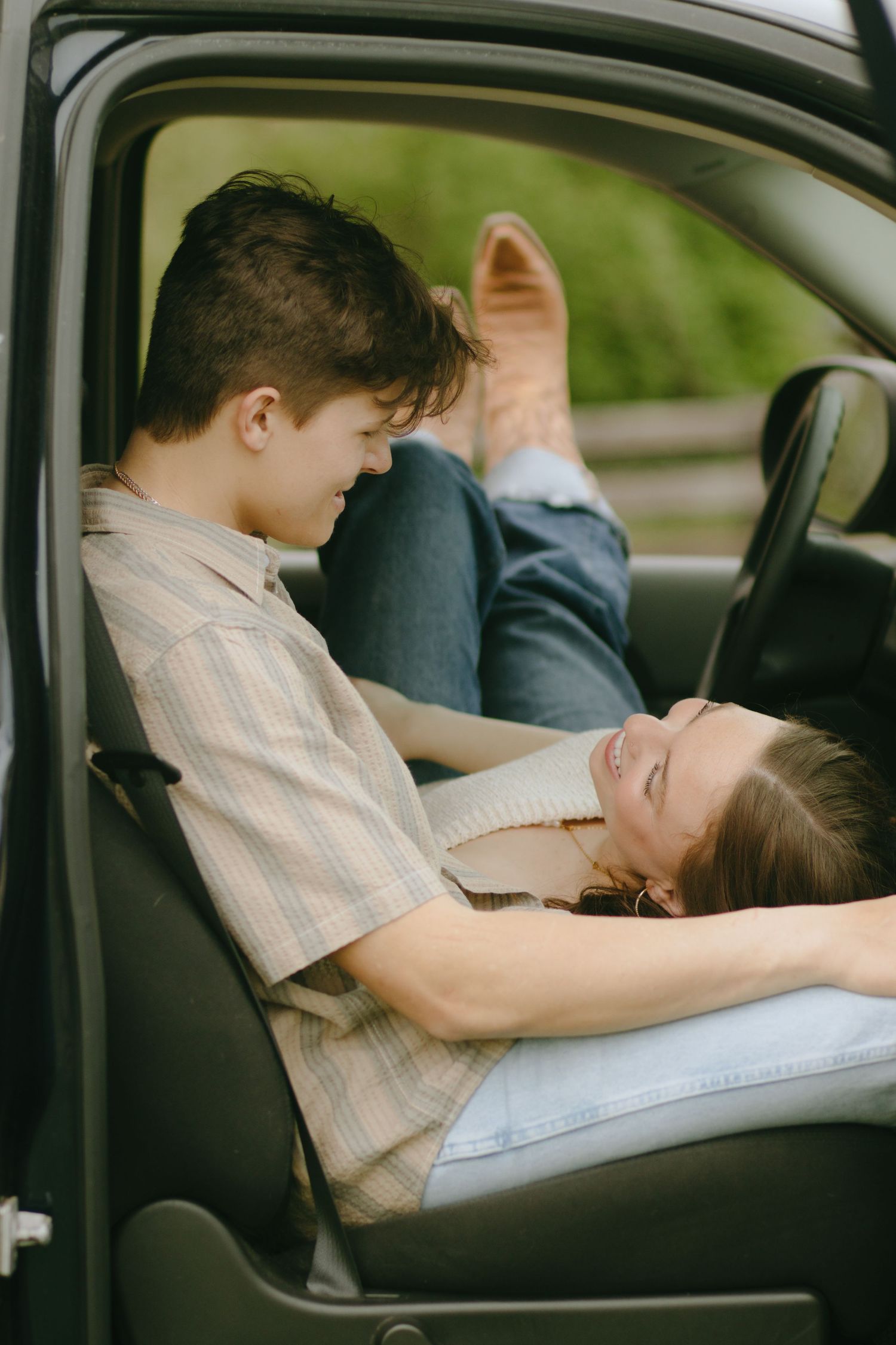Two people share tender moments inside a parked car.