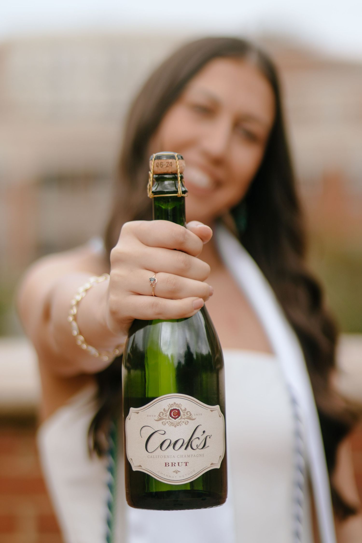 Close-up shot of hands holding a Cooks champagne bottle against a blurred background.