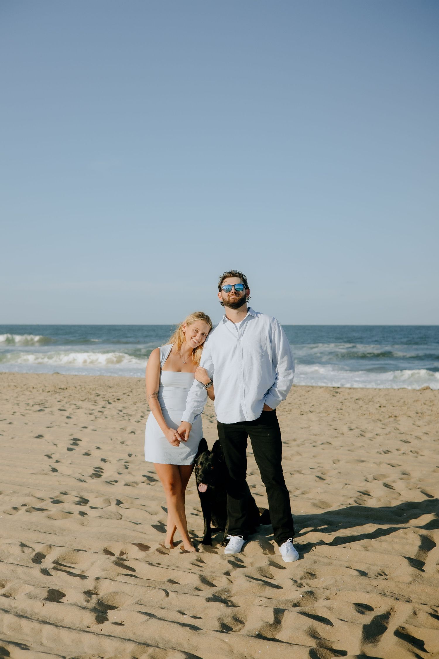 Two people enjoy a sunny day together on a sandy beach by the ocean.