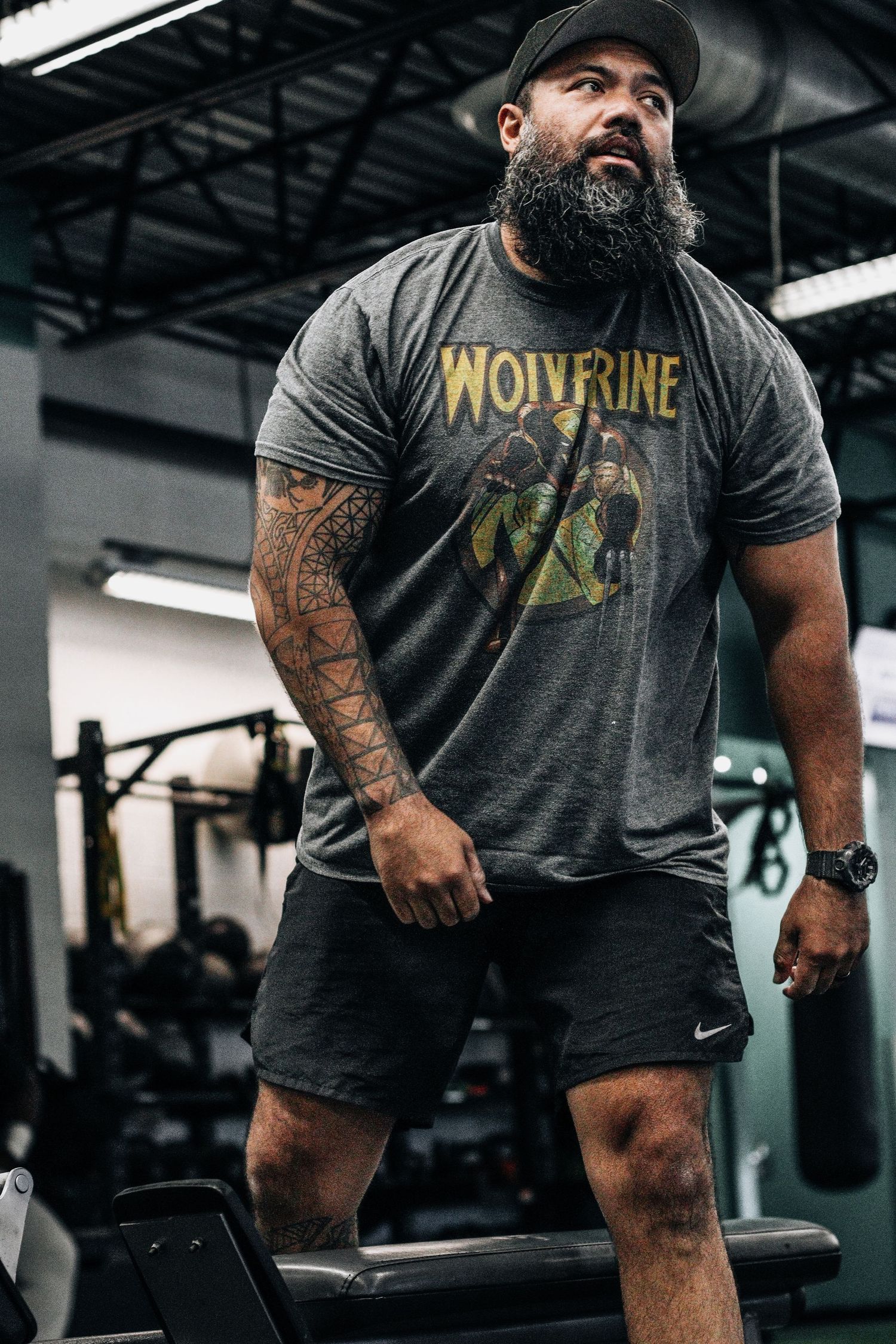 Athletic person wearing a Wolverine t-shirt and shorts performs workout exercises in a gym setting.
