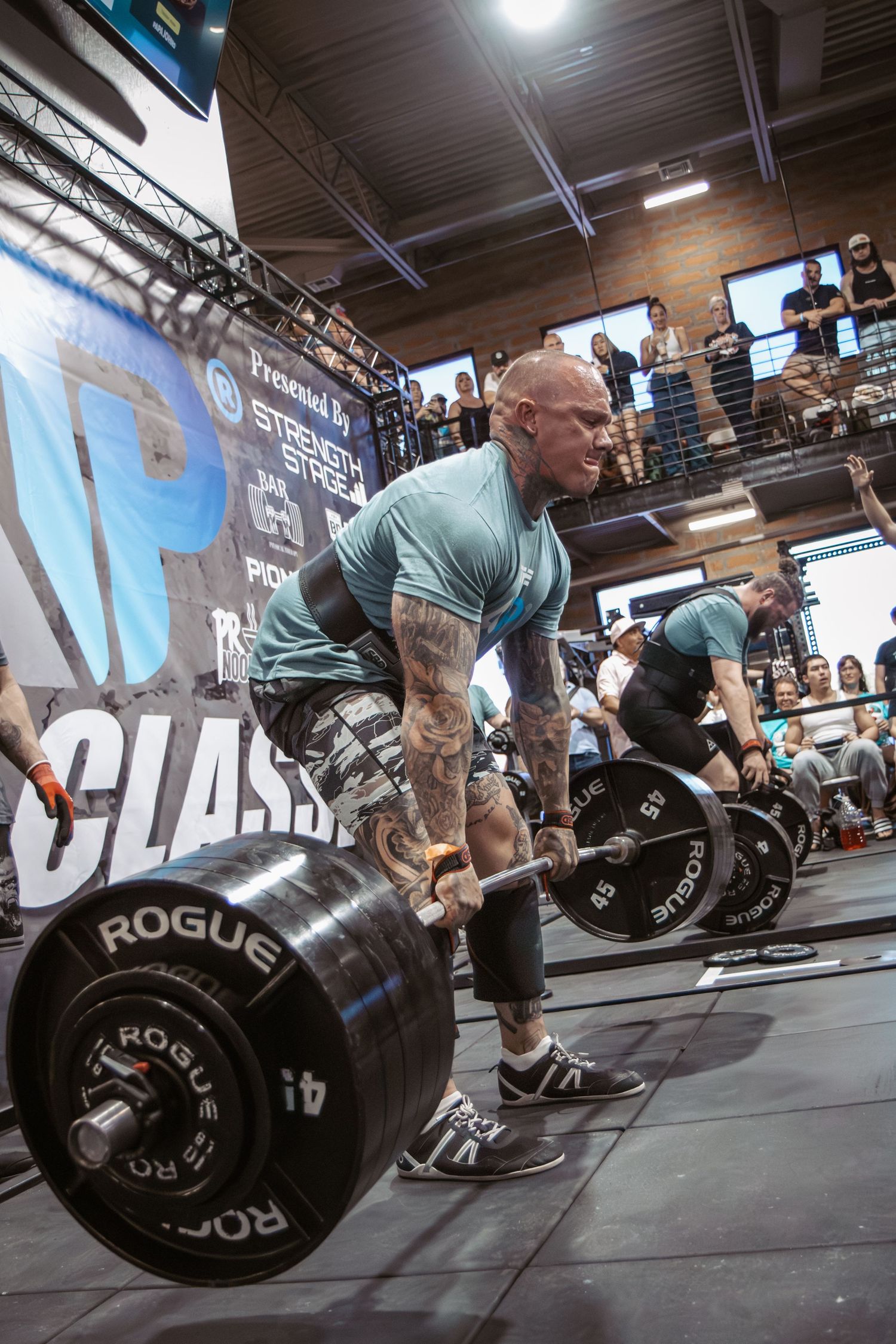 Athletes performing heavy deadlifts with Rogue equipment during a competitive event.