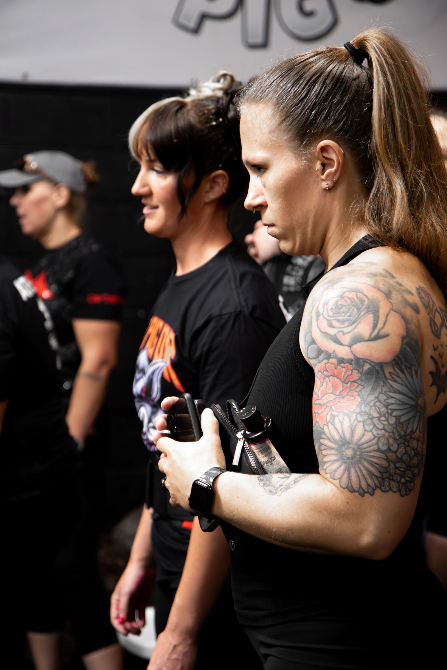 Row of athletes with tattoos and black shirts training in a gym.
