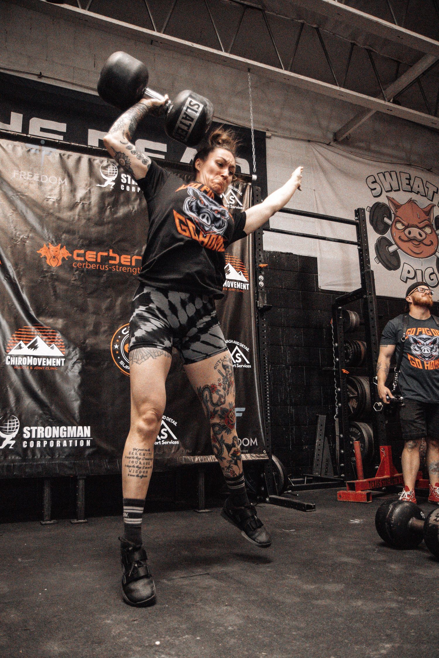 Dynamic shot of athlete executing kettlebell snatch movement in training facility.
