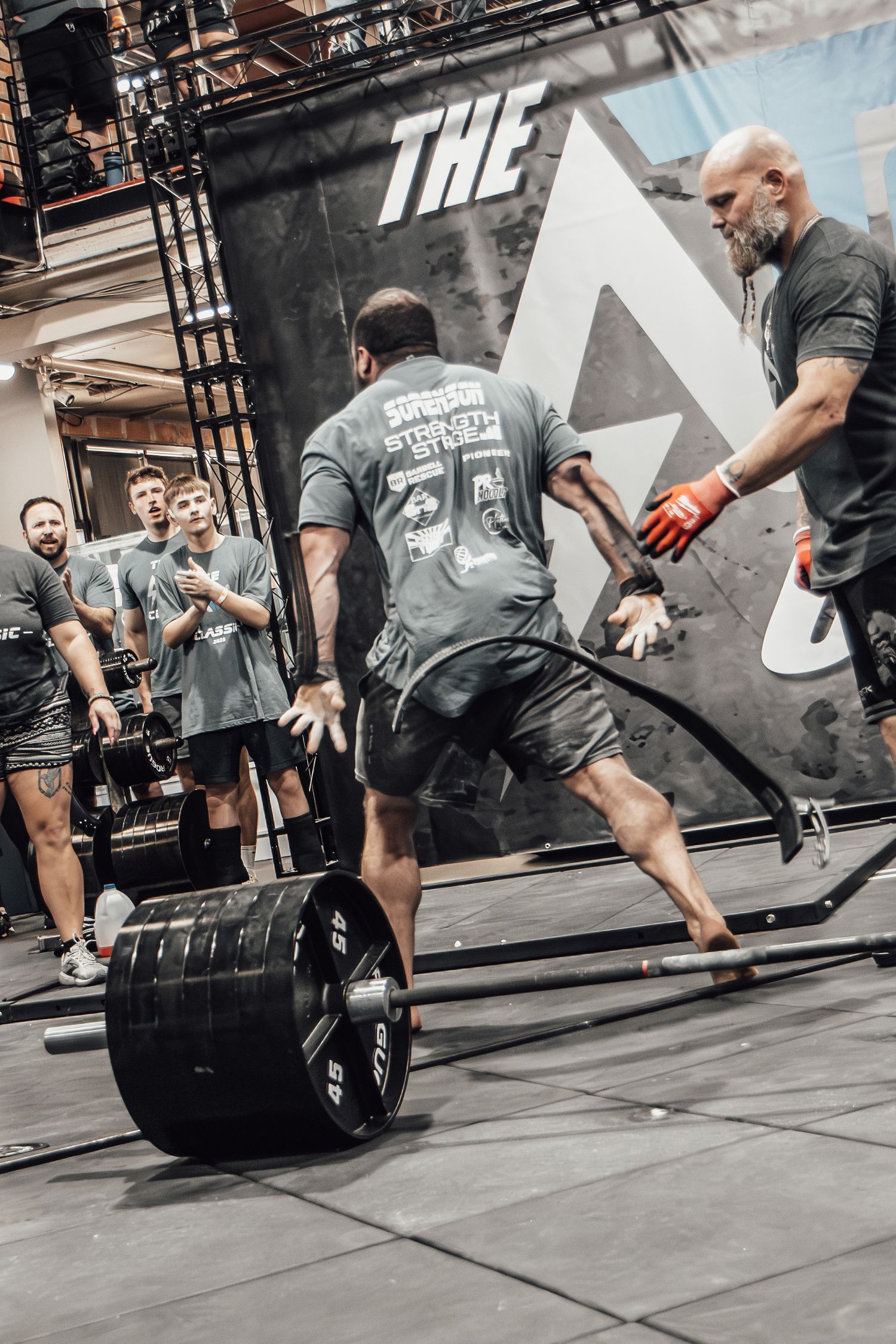 Athletes demonstrating proper deadlift form with heavy weights during a competitive event.