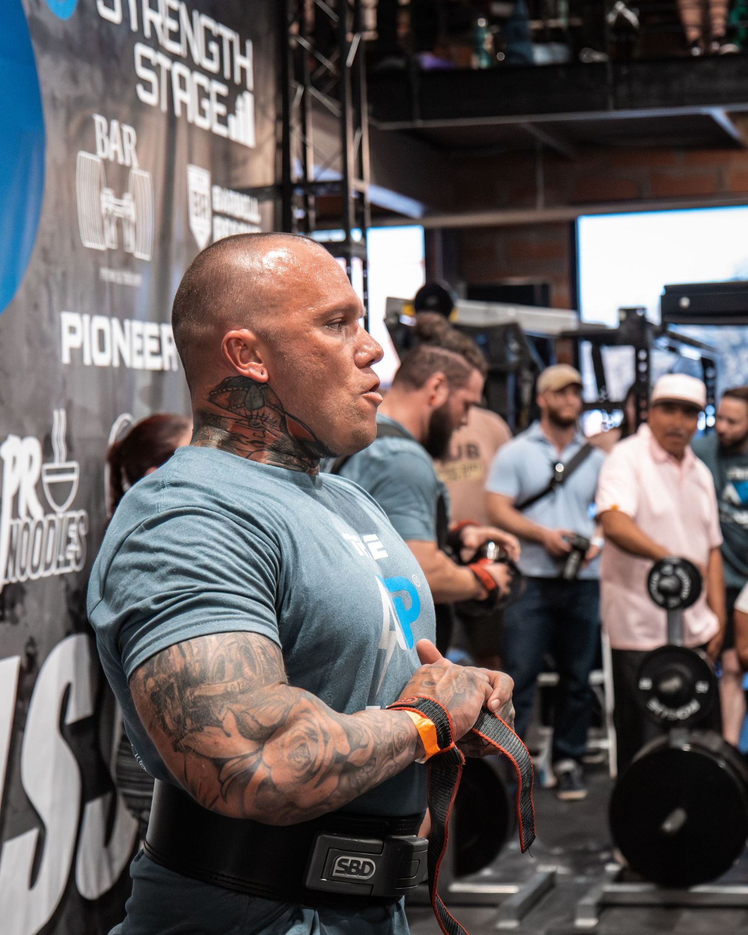 Athletes demonstrating intense effort during a weightlifting competition with branded equipment.