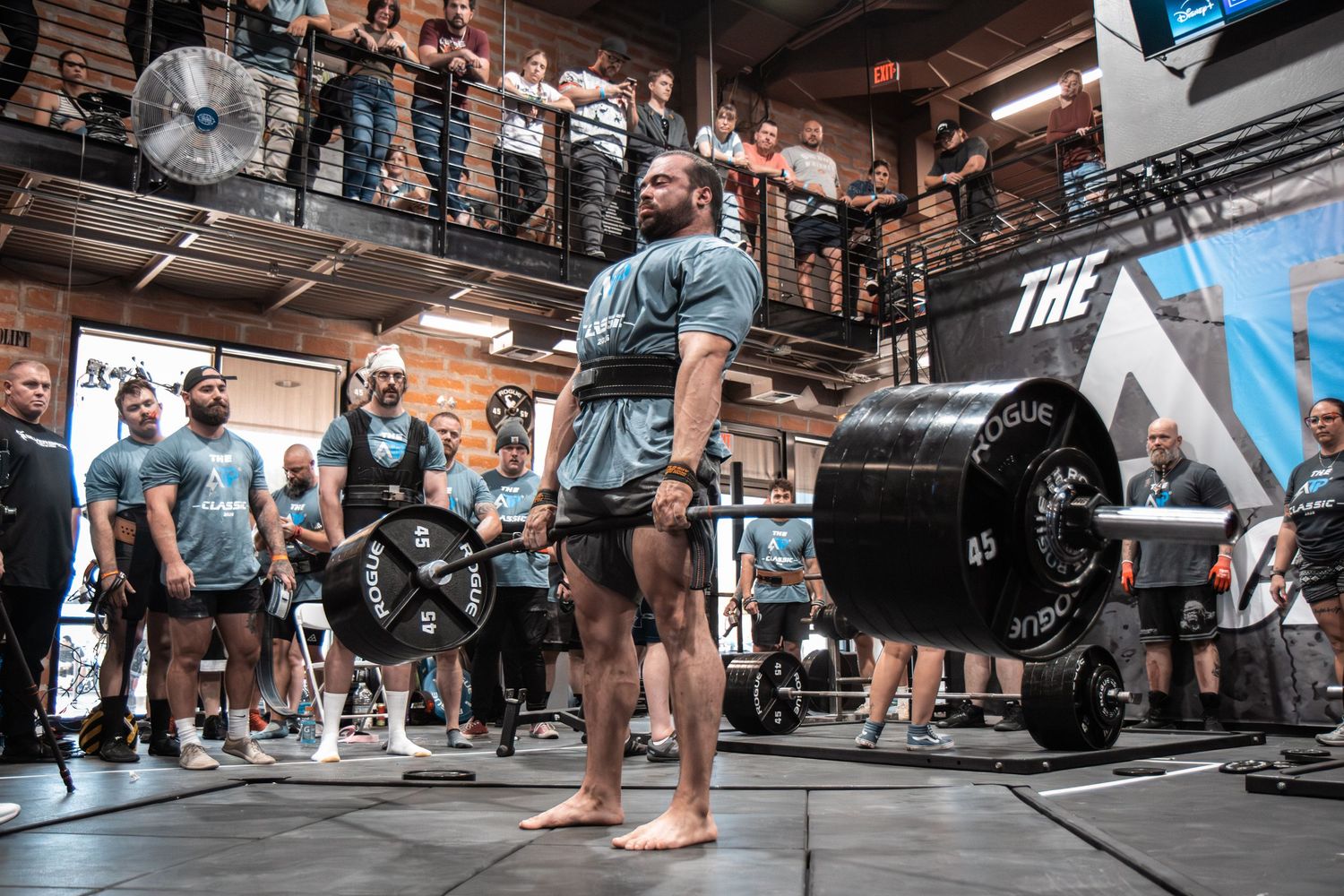 Multiple athletes lifting heavy barbells in synchronization during a competitive weightlifting event.