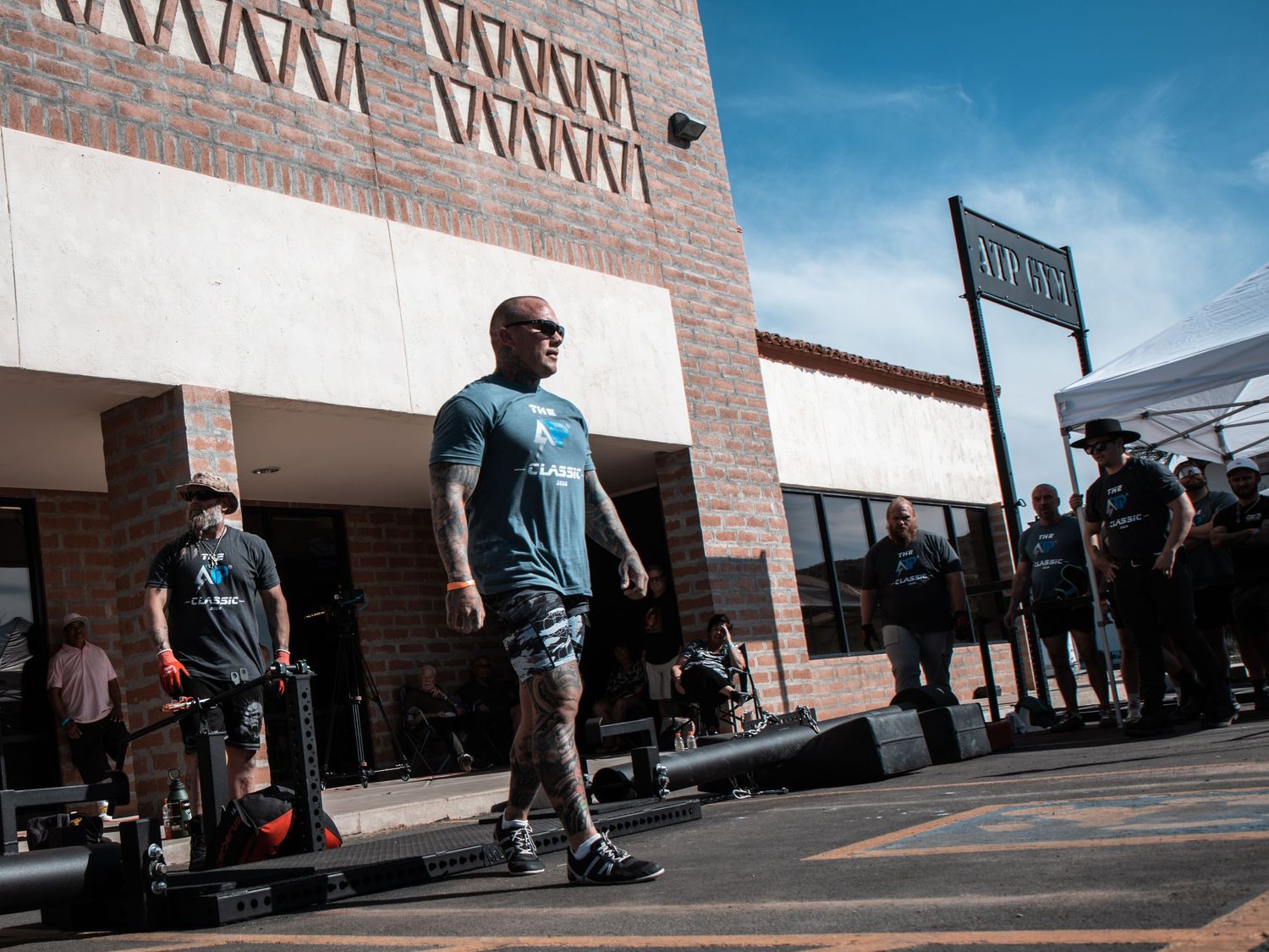 Athletes warming up outside a brick building before a strength competition event.
