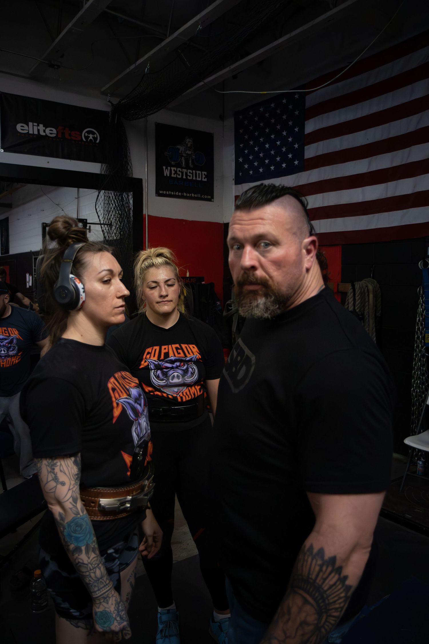 Athletes training in a dark gym space with American flags on the wall.