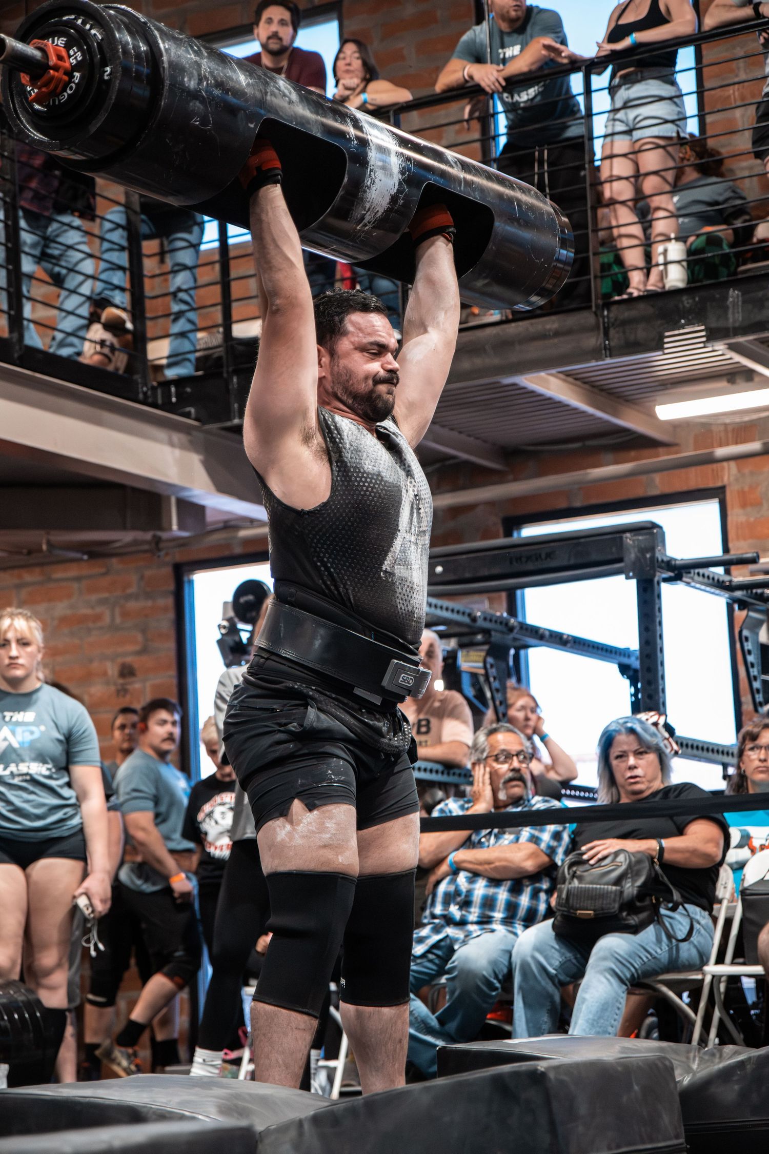 Athletes performing overhead lifts with heavy barbells during a competitive event. Strongman Log press at ATP Gym in Phoenix AZ
