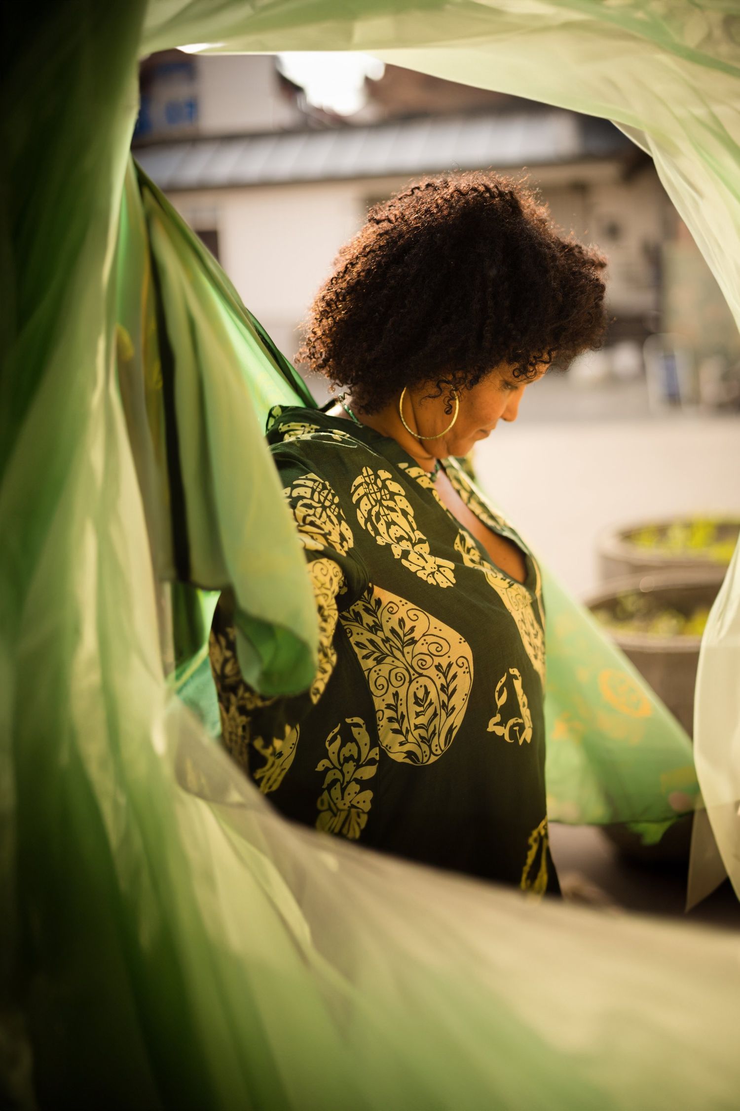 Person wearing patterned green clothing seen through tropical foliage.