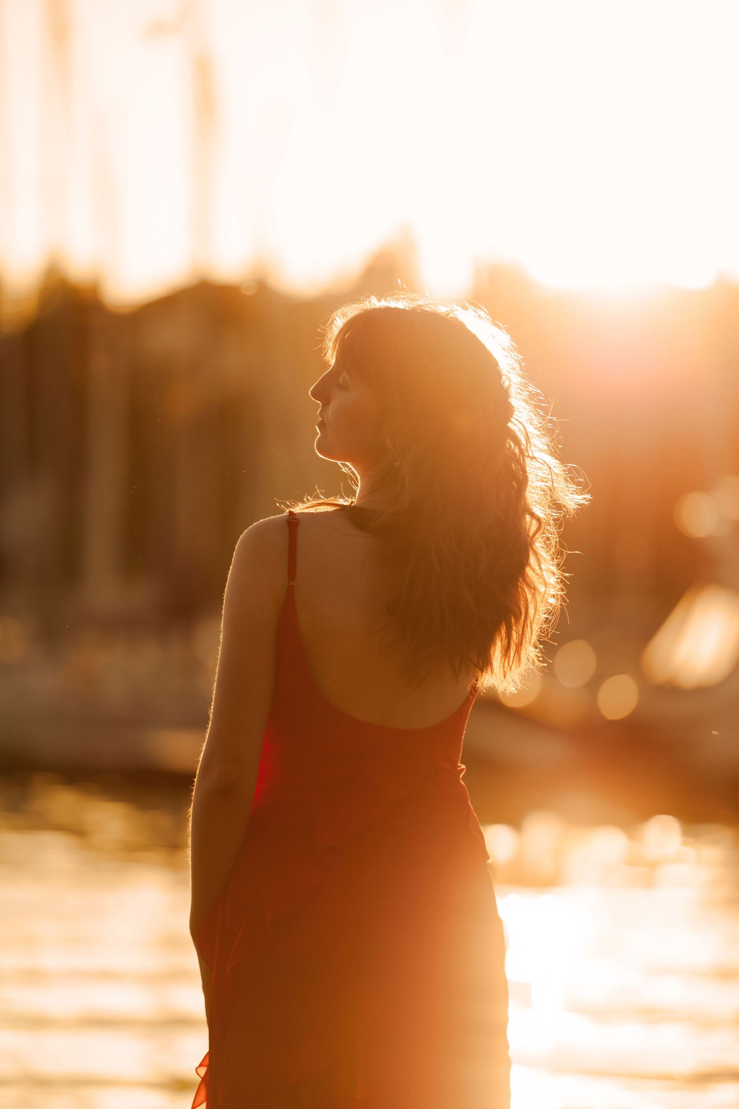 Silhouetted figure backlit by warm sunset glow near water.