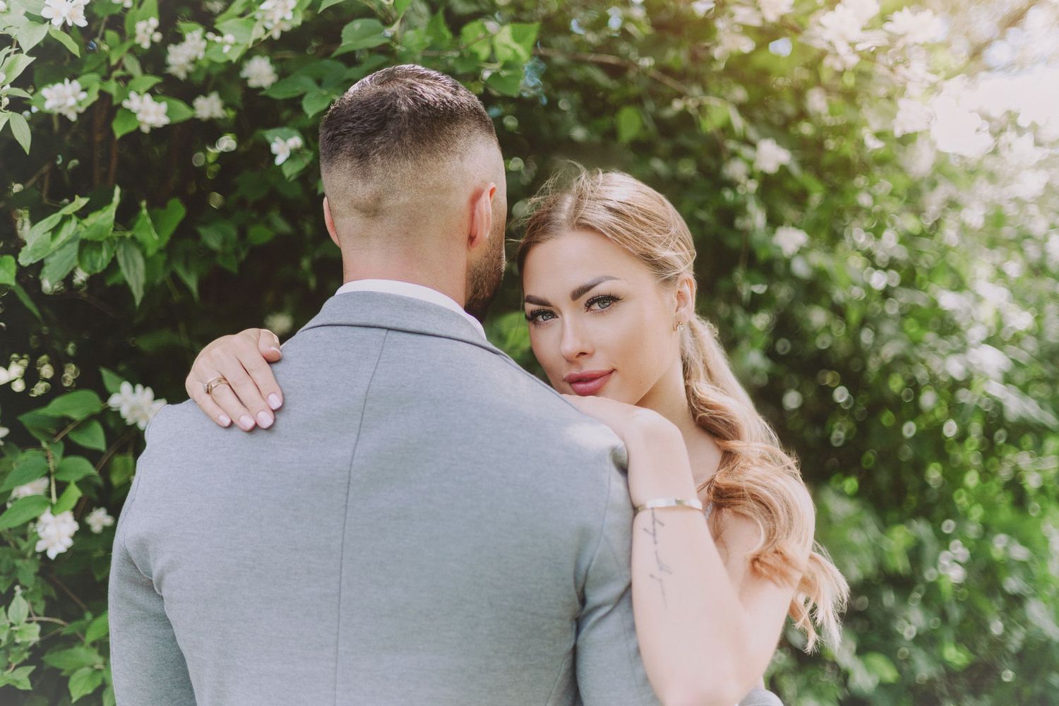 A romantic couple shares tender moments in a lush garden setting during a wedding photoshoot.