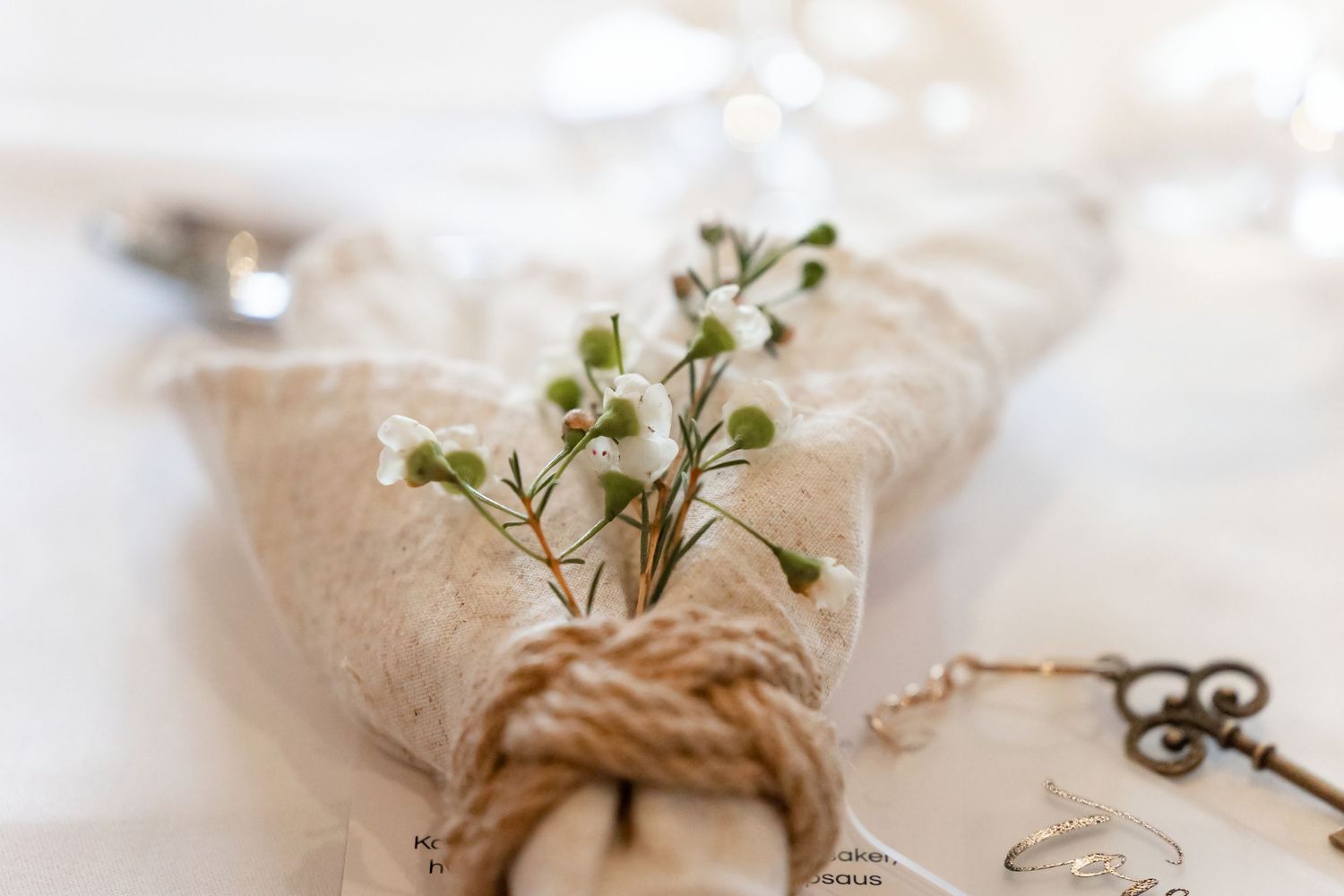 White lace and burlap wedding napkin rings with delicate floral accents and pearls on a light background.