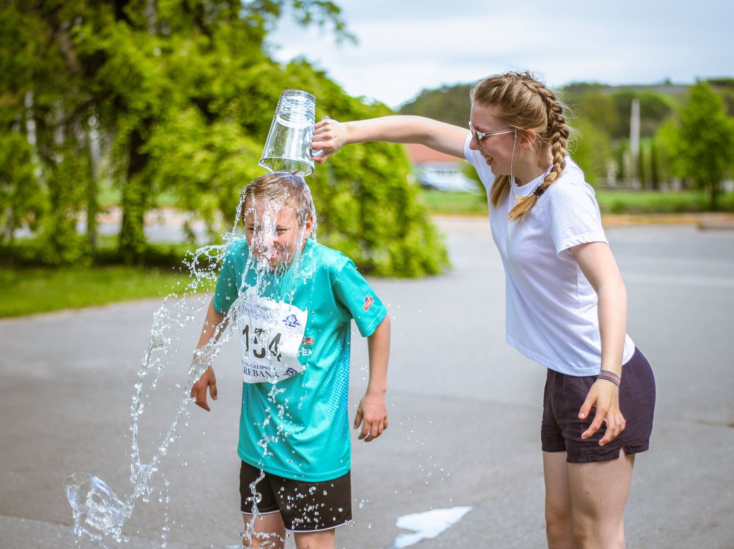 A person splashes water from a glass jar on a sunny summer day outdoors.