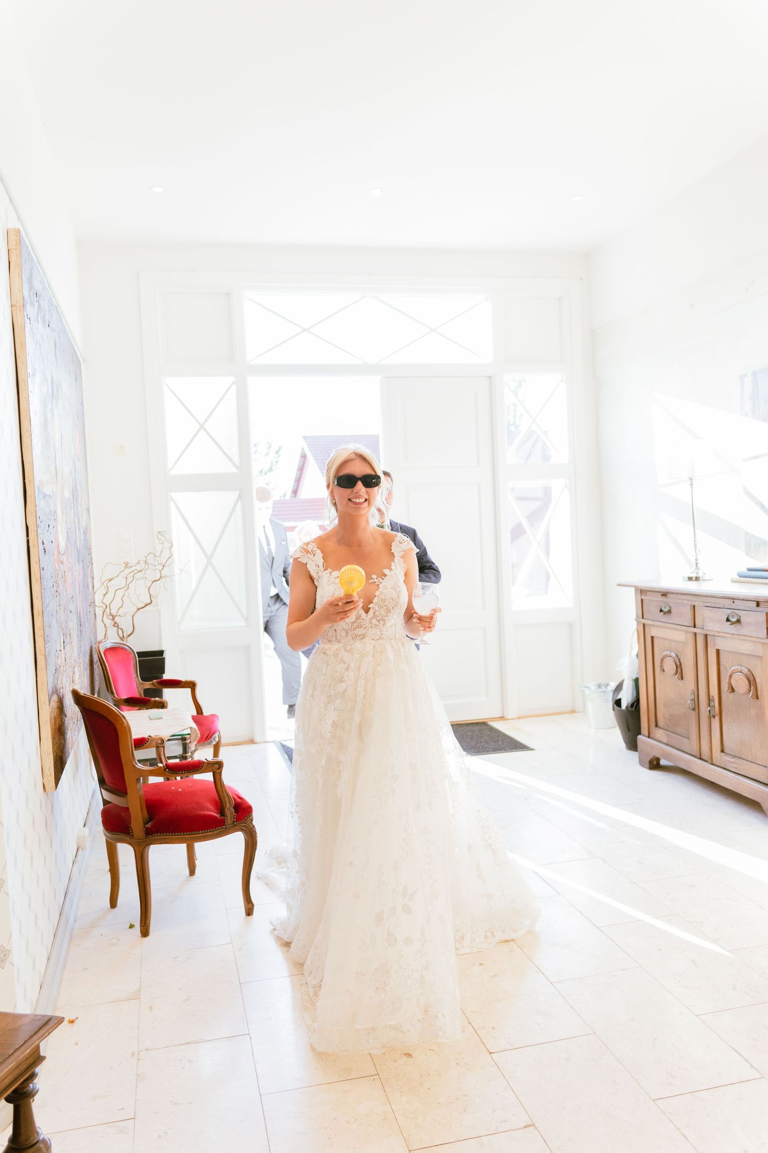A bridal preparation room with sunlit windows showcases an elegant wedding dress and vintage-style furniture.