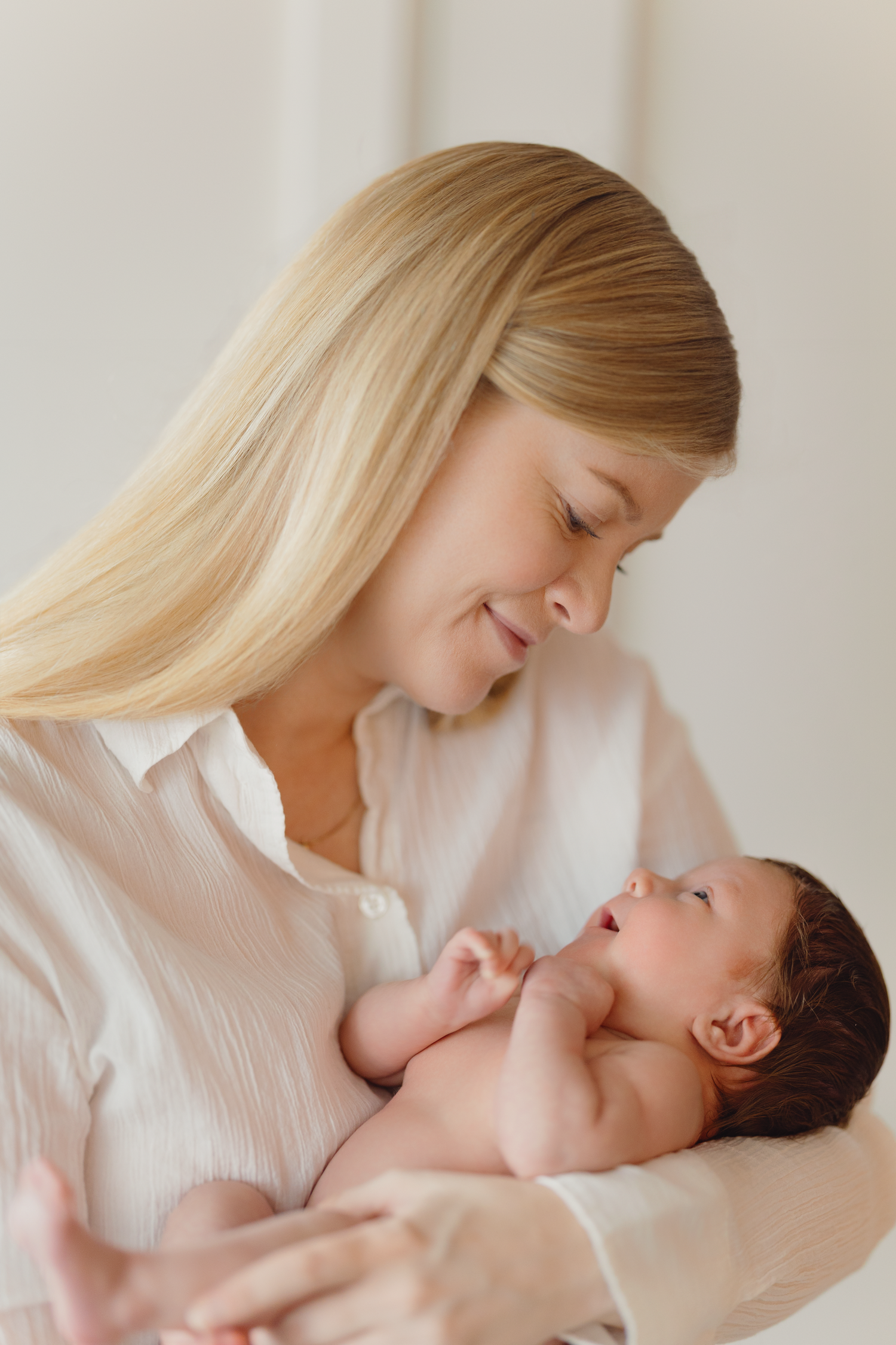 A tender moment between parent and newborn baby shown in four progressive shots against a light background.