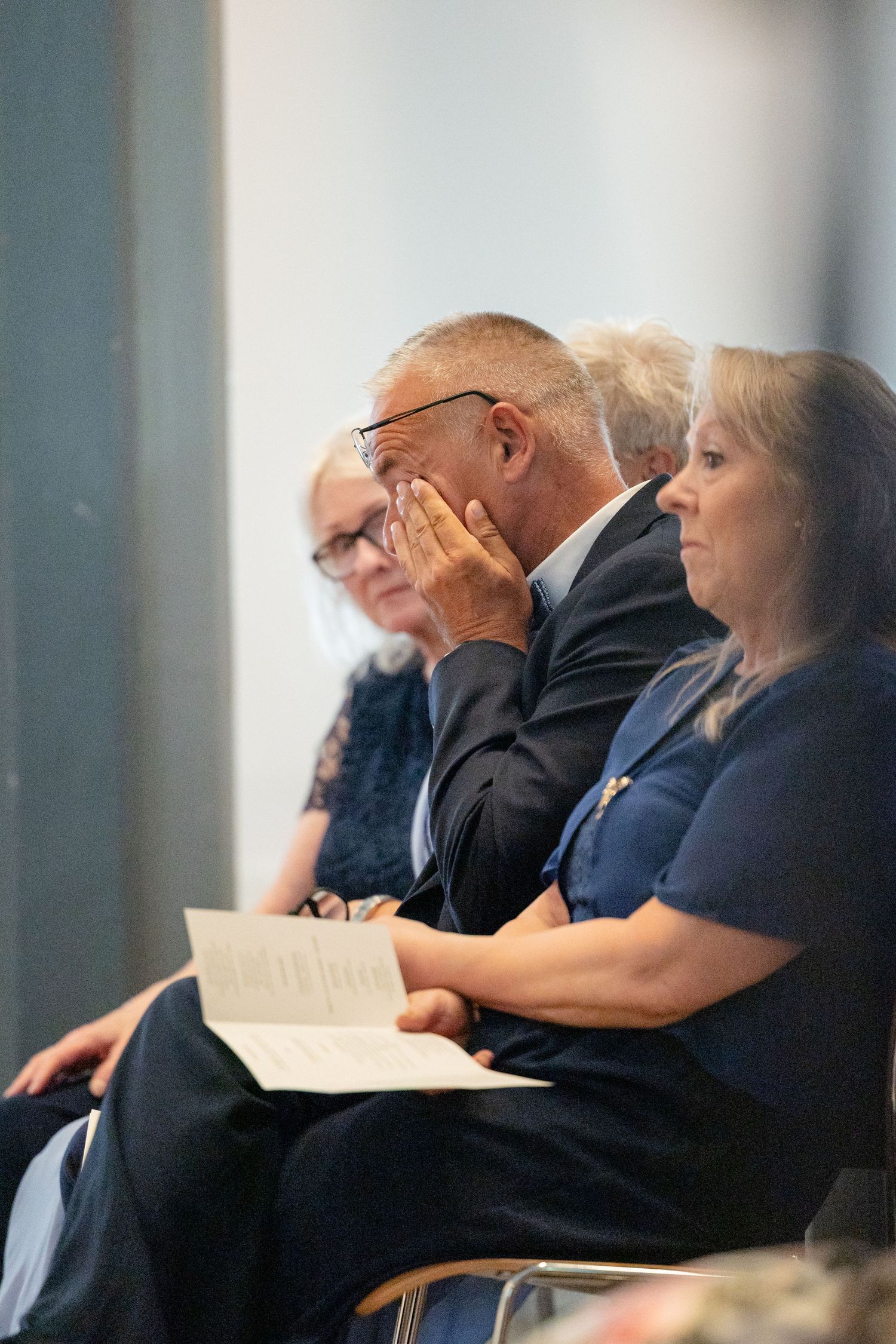People sit together in a row at what appears to be a conference or meeting, taking notes and paying attention.