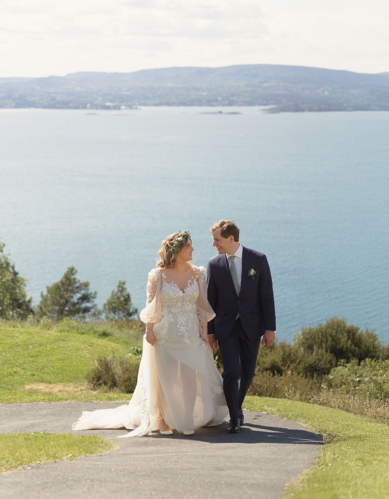 A couple sits together on a scenic coastal overlook with sweeping ocean views in the background.