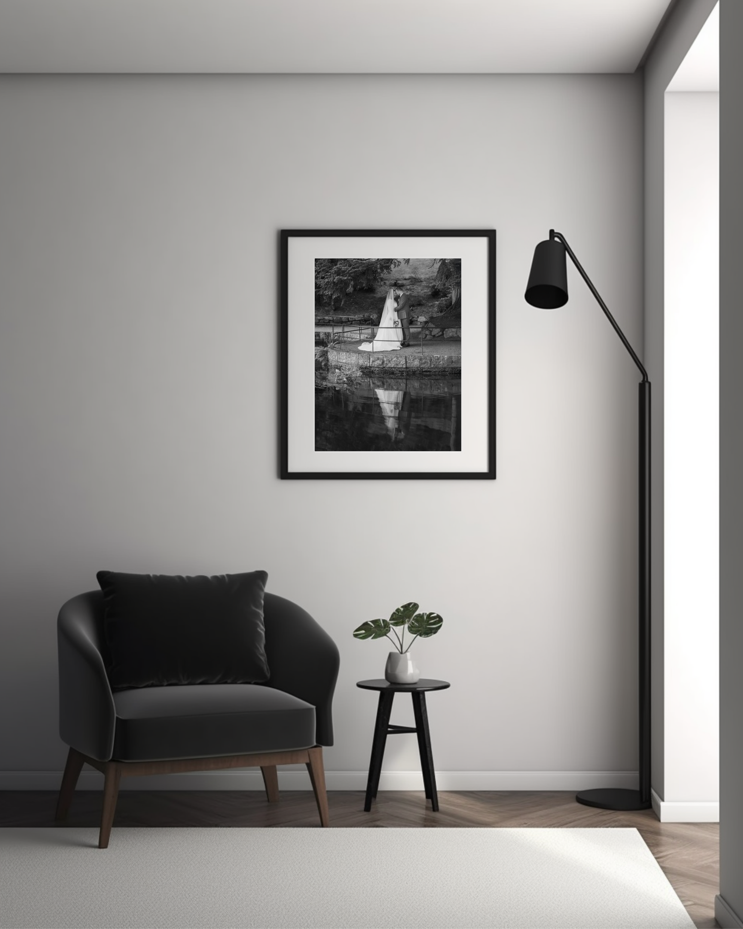 Minimalist living room corner with black armchair, framed black and white photograph, floor lamp and small side table.