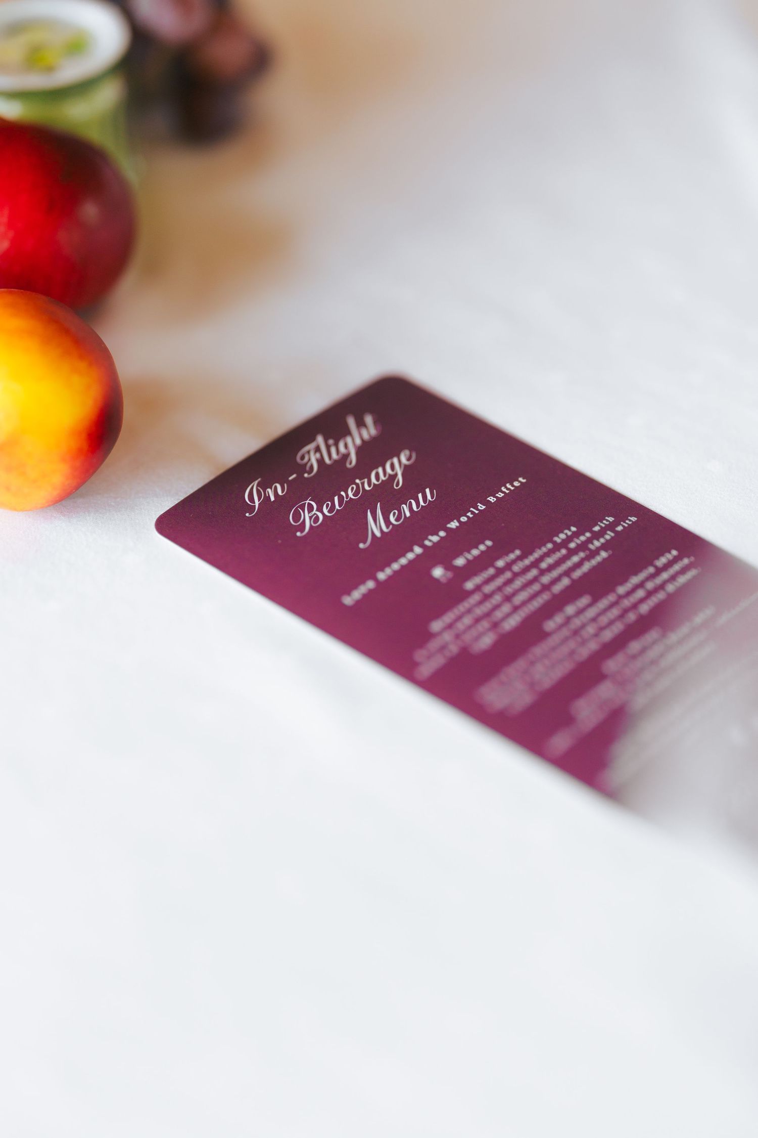 A series of burgundy bar menu cards shown at different angles with fresh fruits and blurred background.
