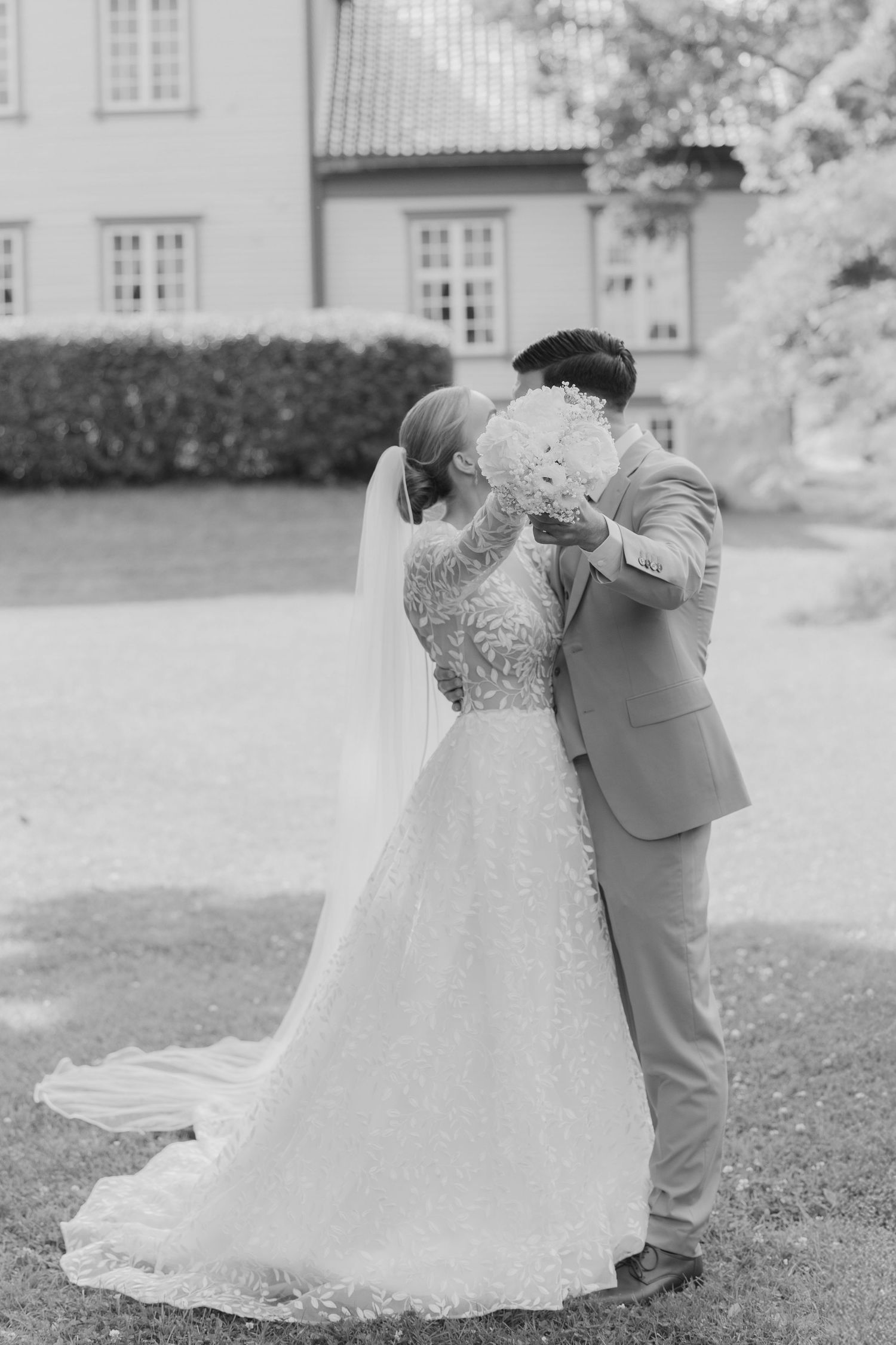 Black and white wedding photo series showing couple dancing together on grass outside a building.