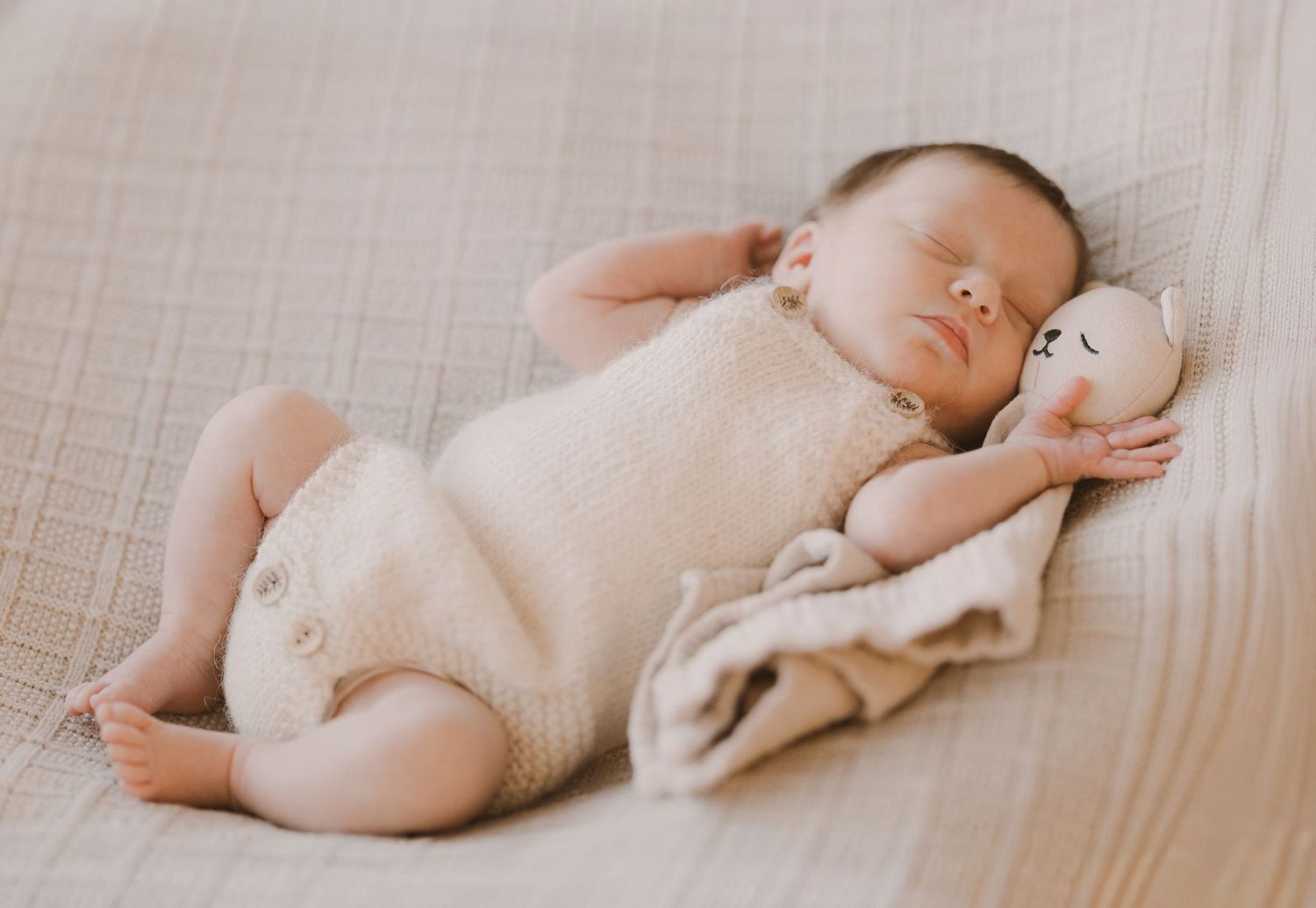 A series of minimalist photos showing a baby lying on a light colored blanket in various sleeping positions.