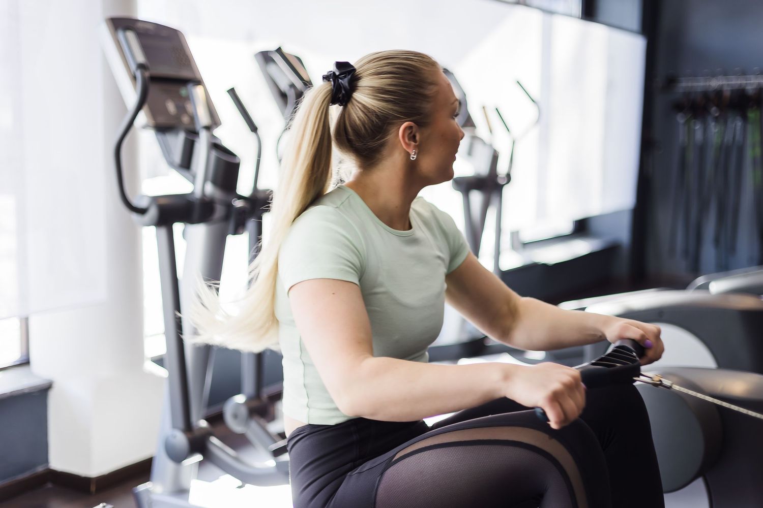 Person exercising on a stationary bike in a modern fitness gym with cardio equipment in background.