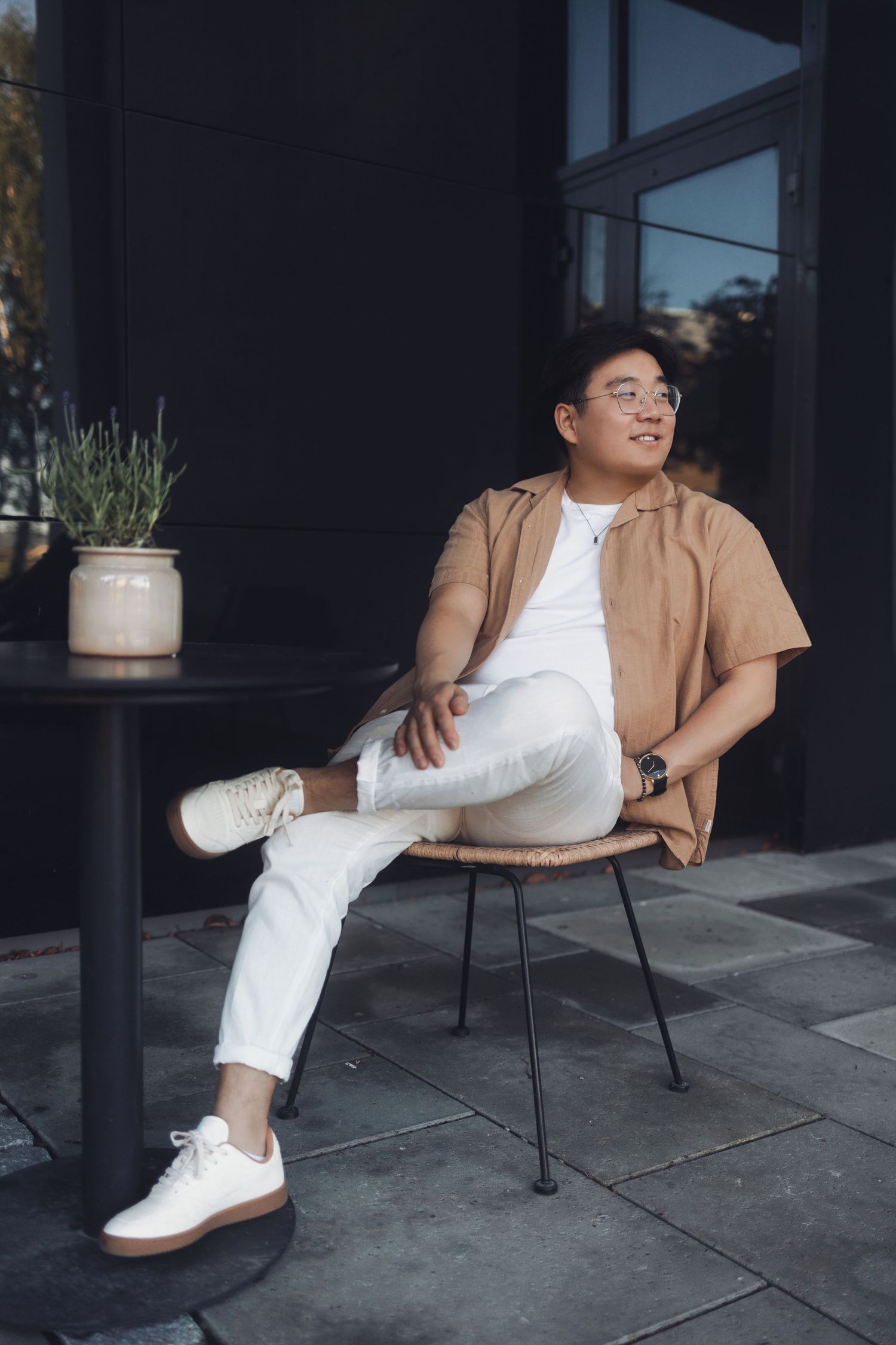 A stylish fashion photo series showing a brown jacket and white pants outfit styled with white sneakers on a concrete patio.