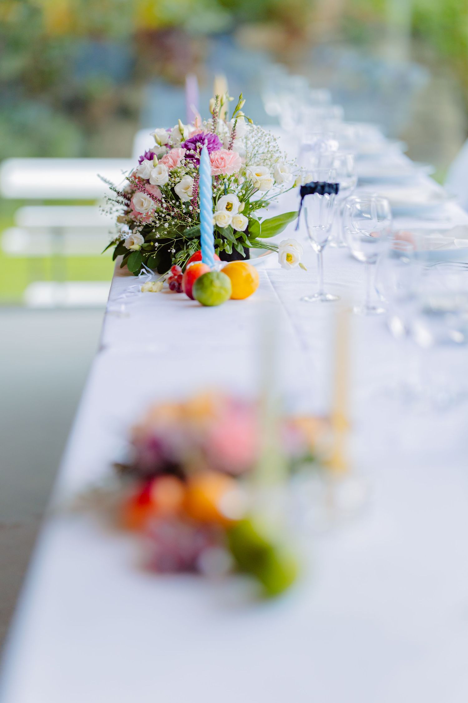 Elegant table setting with delicate floral arrangements and blurred glassware creating a soft, romantic atmosphere.