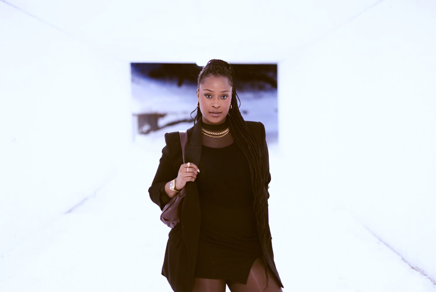 A person in a black turtleneck sweater poses with expressive hand gestures against a white background.