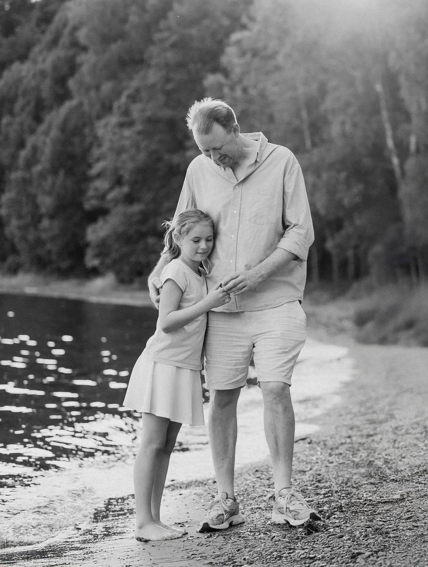 Parent and child walking together along a serene lakeshore in a series of black and white photographs.