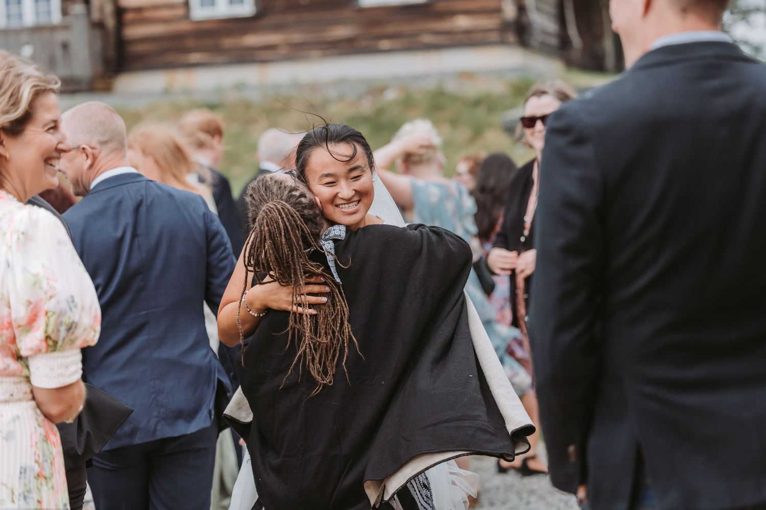 Wedding guests laugh and embrace during an outdoor reception celebration.