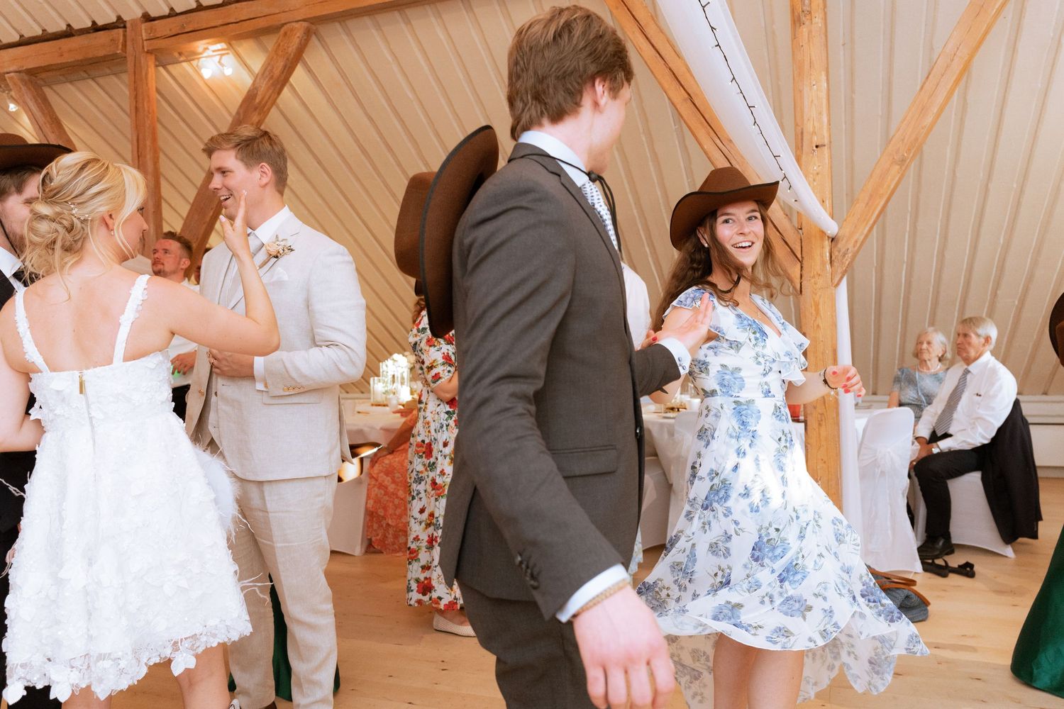 Wedding celebration inside a rustic wooden barn venue with guests dancing and mingling on the dance floor.