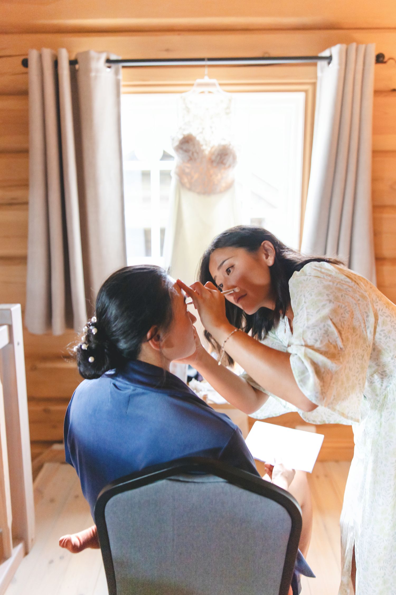 A couple in formal wedding attire share an intimate moment while seated in a rustic cabin setting.