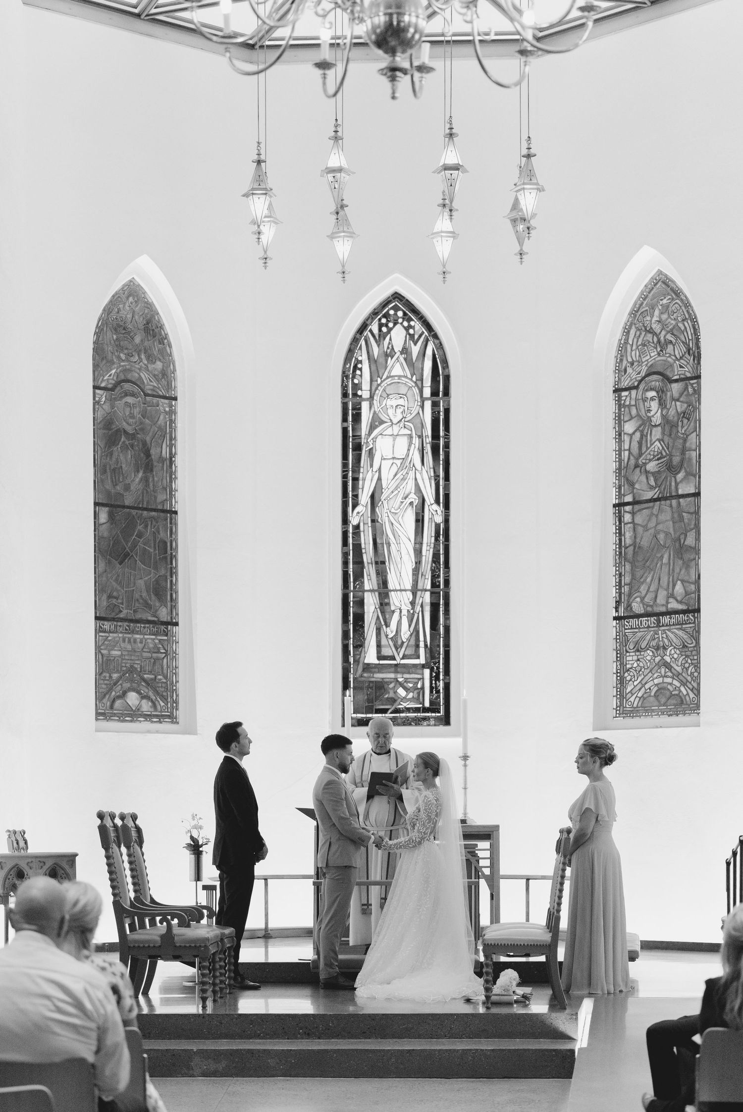 A church interior with stained glass windows and people gathered for a ceremony.