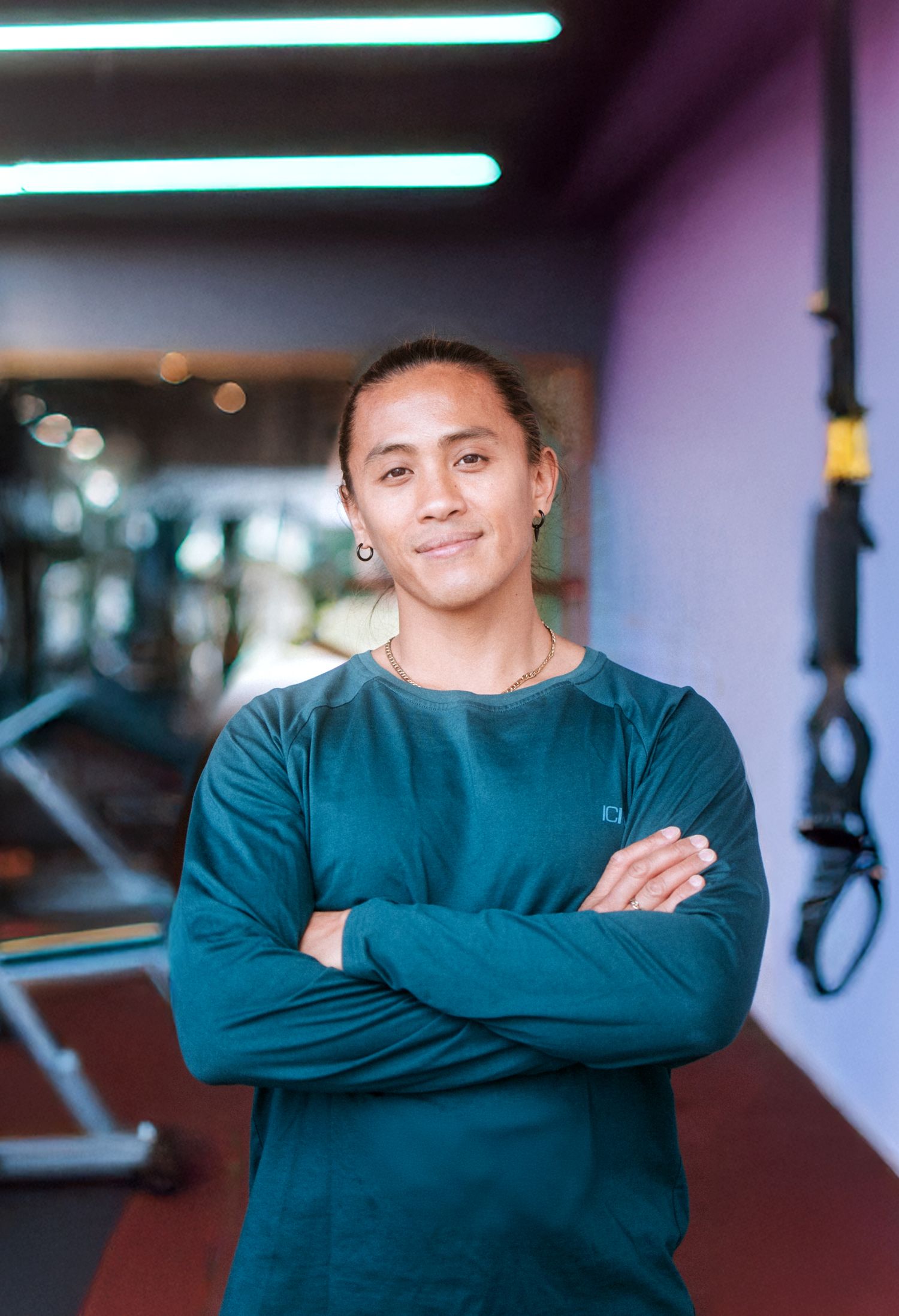 Athletic person in teal sweatshirt posing in gym environment.