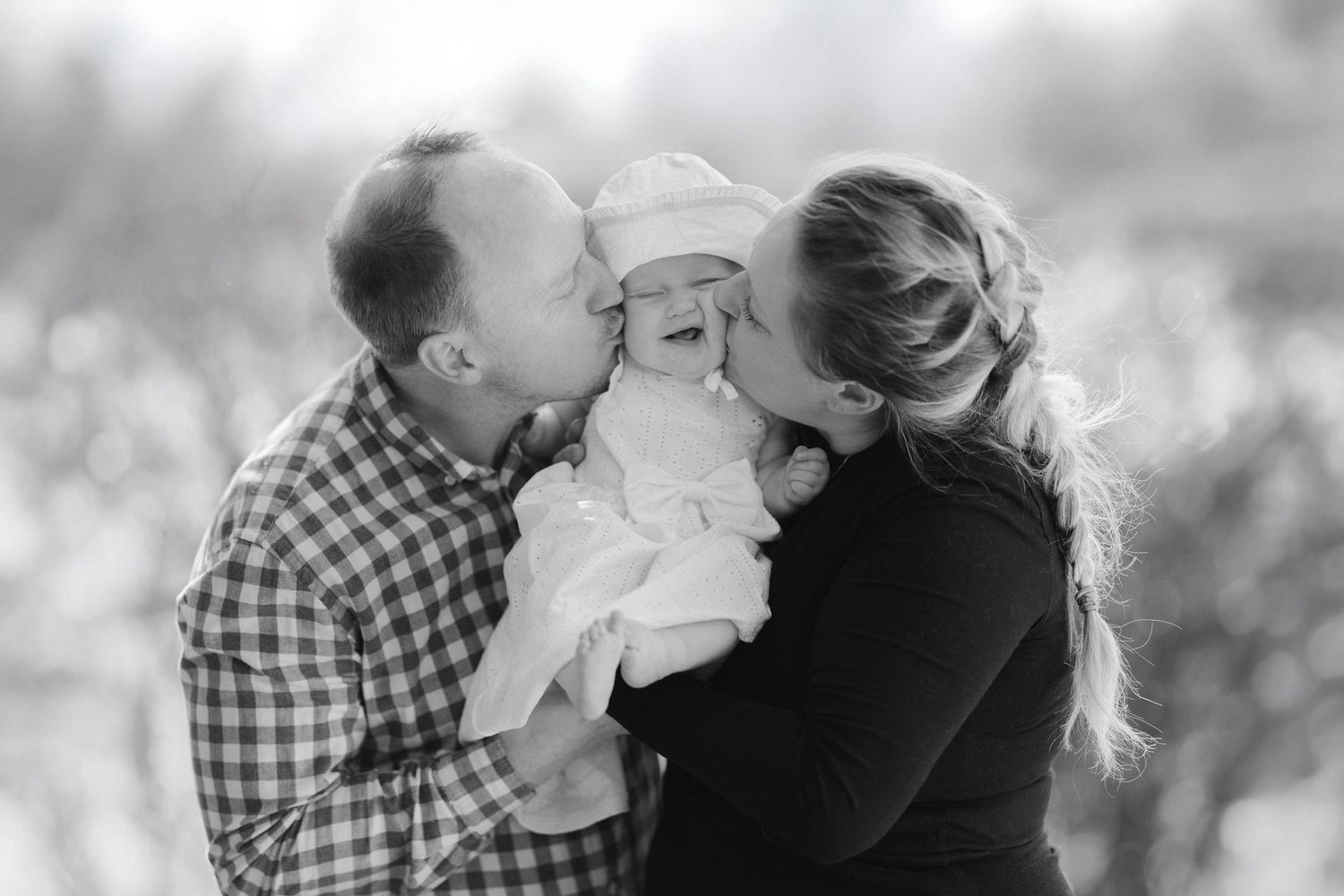 Black and white photo collage showing intimate family moments with parents and baby in outdoor settings.